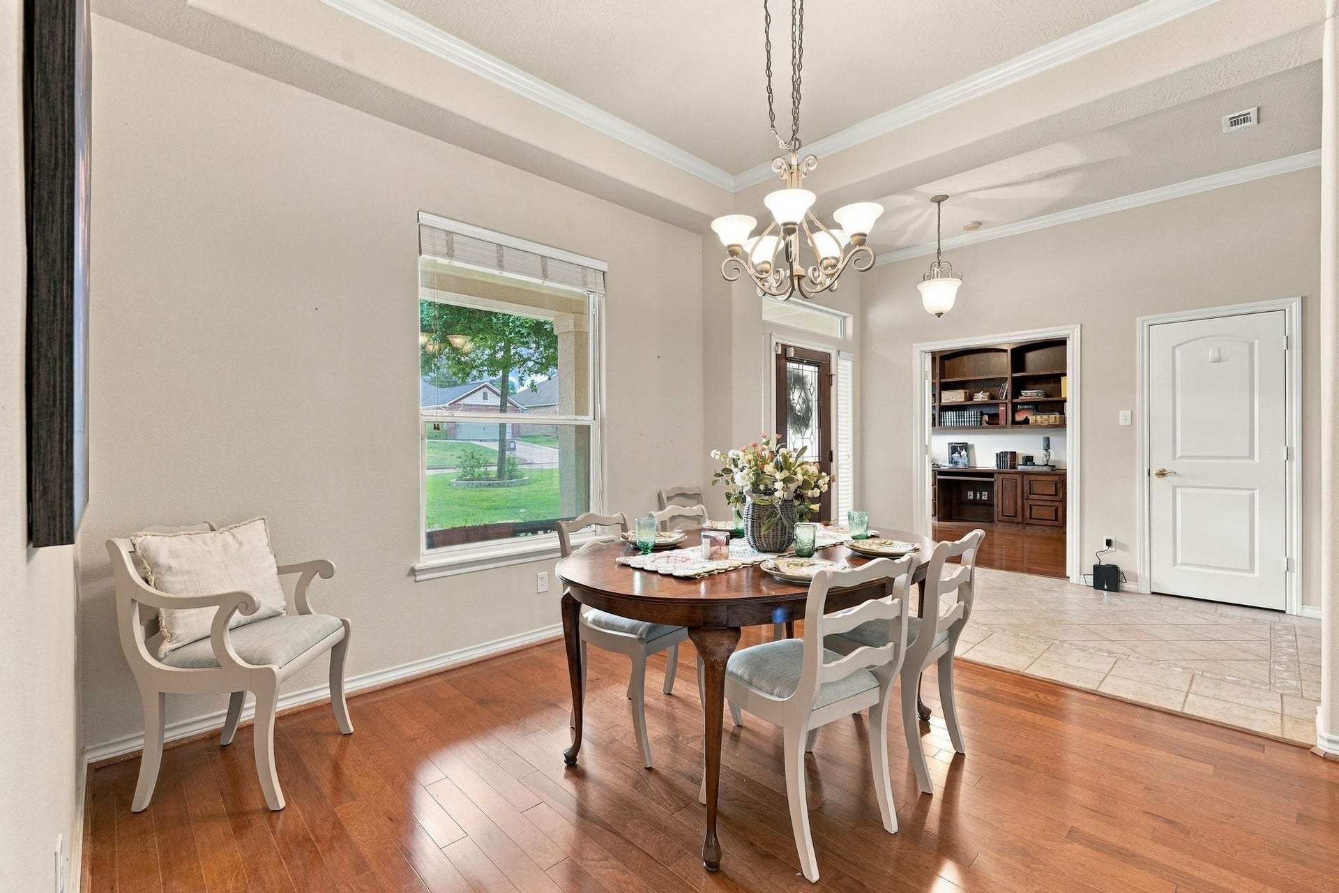 156 April Waters Drive W, Conroe, TX 77356 Spacious dining area with engineered hardwood floors, a sophisticated chandelier, and ample natural light. Adjacent to an office/Study with built-in desk and shelving.