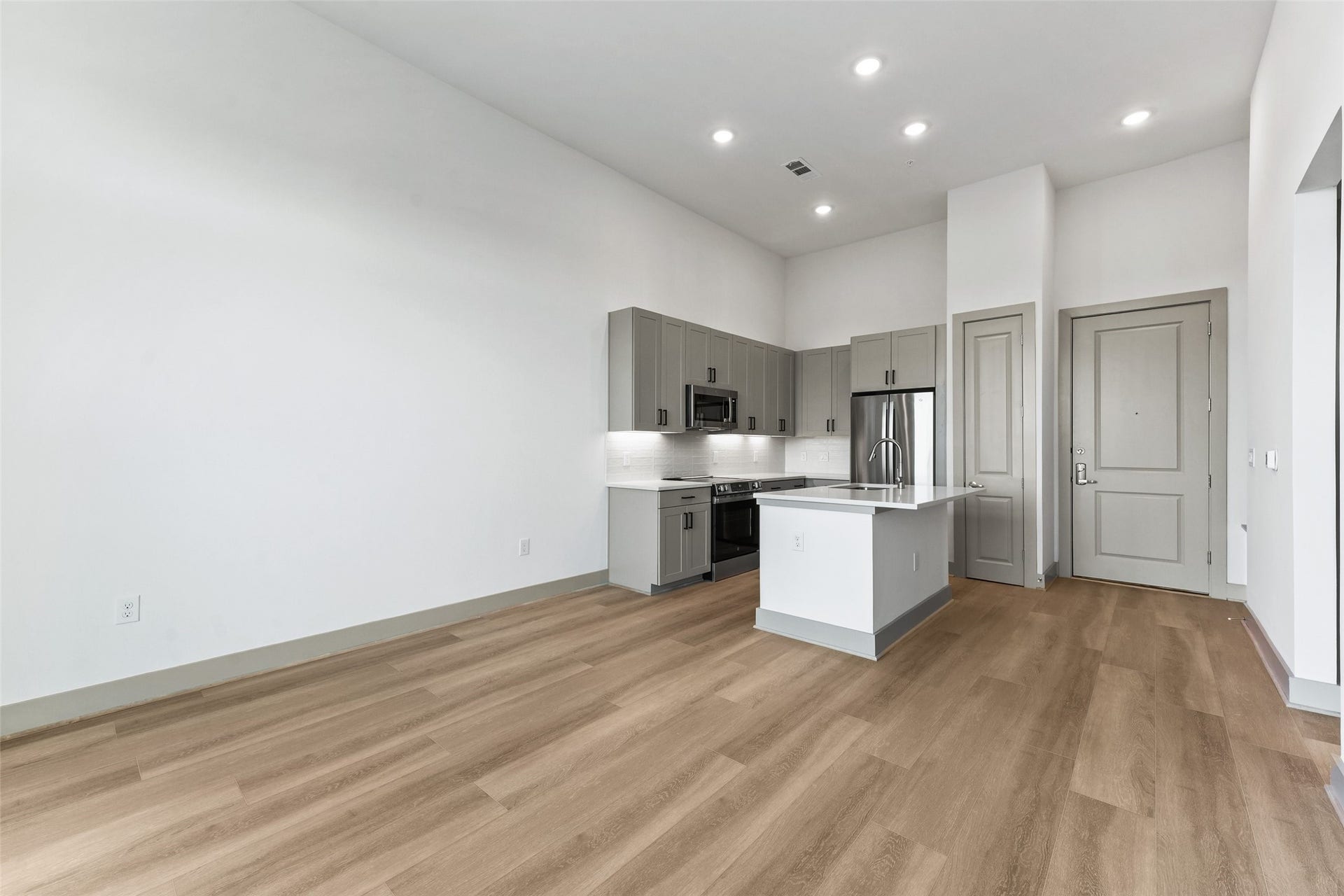 170 Malone Street, #3402, Houston, TX 77007 This modern kitchen features sleek gray cabinetry, stainless steel appliances, and a spacious island. It has an open layout with light wood flooring, recessed lighting, and ample natural light, creating a bright and inviting space perfect for cooking and entertaining.