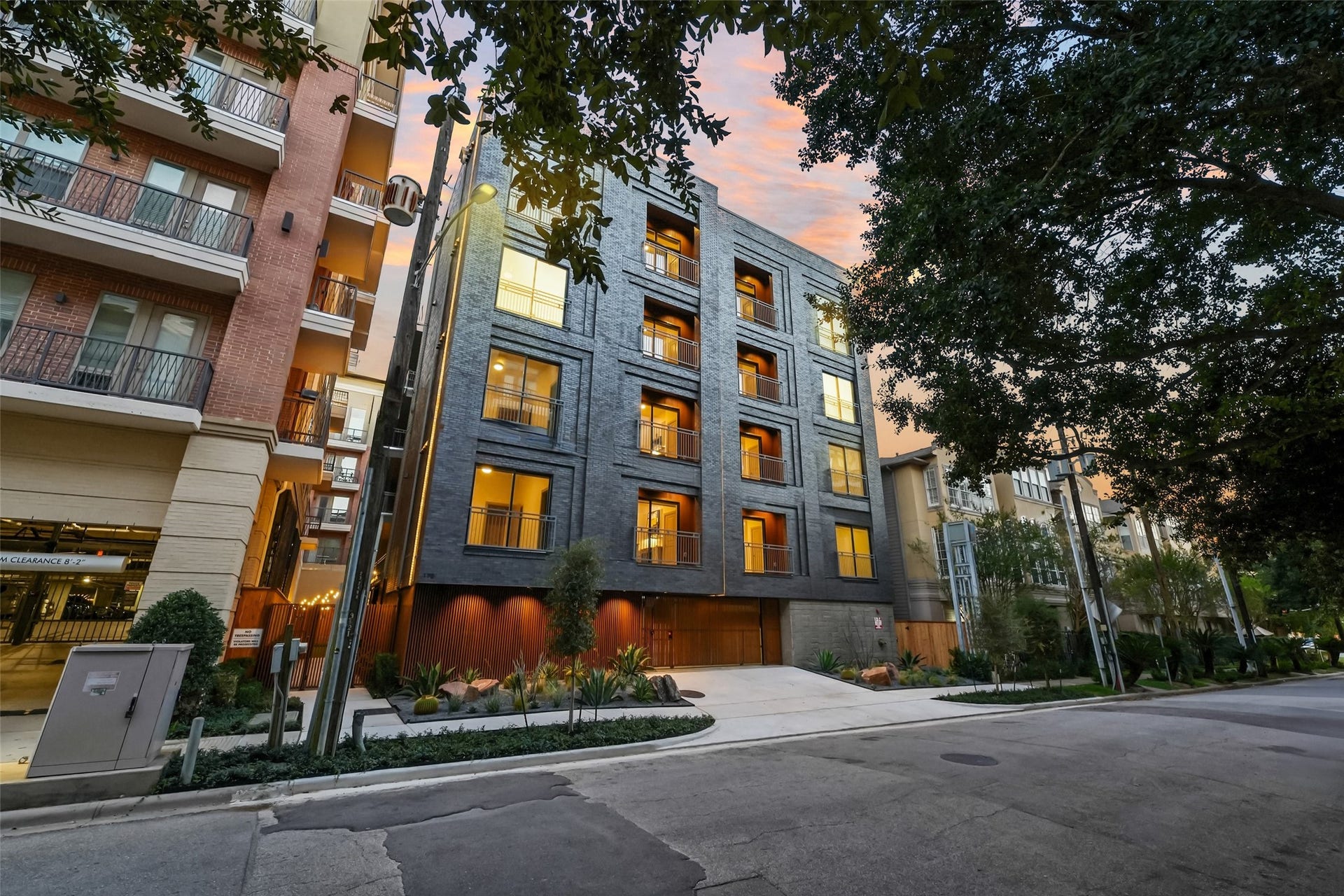 170 Malone Street, #3402, Houston, TX 77007 This modern apartment building stands out with its sleek, dark exterior and large windows, offering a contemporary urban living experience. Surrounded by trees and neighboring buildings, it features a well-maintained entrance and is situated on a quiet street, perfect for potential home buyers seeking a blend of style and convenience.