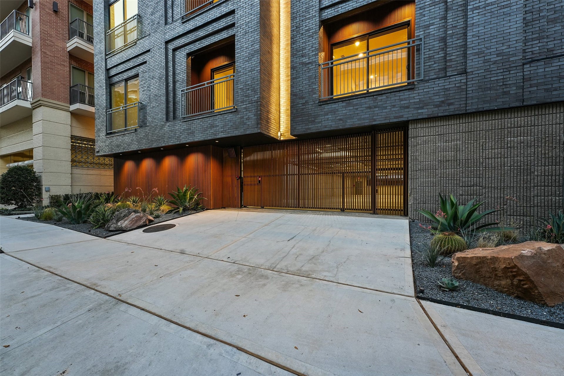 170 Malone Street, #3402, Houston, TX 77007 This modern apartment building features an elegant exterior with dark brickwork, warm lighting, and stylish metal accents. The entrance is framed by contemporary landscaping, including rocks and succulents, offering a welcoming and upscale appearance.