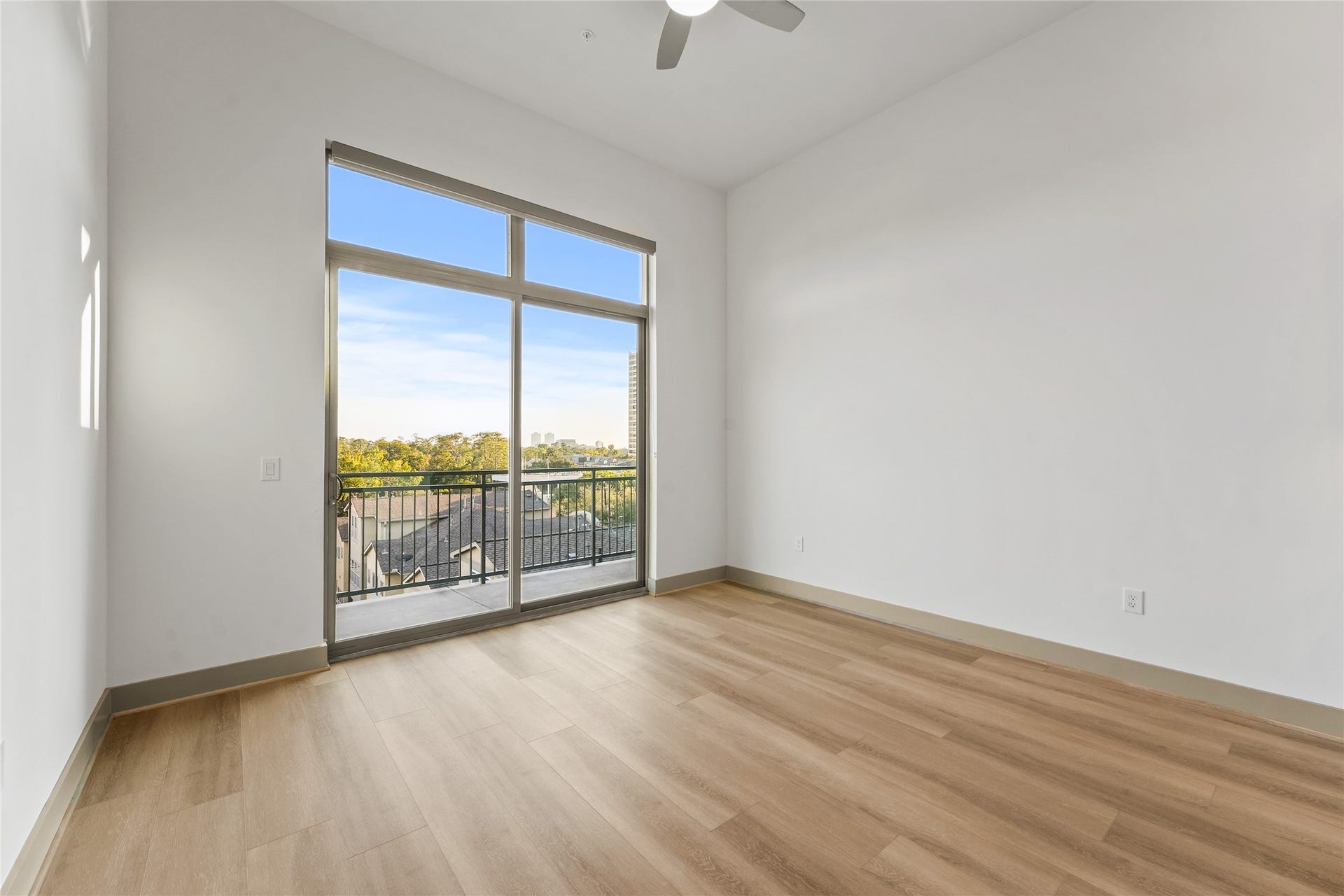 170 Malone Street, #3402, Houston, TX 77007 This room features large windows with a scenic view, plenty of natural light, light wood flooring, and a modern ceiling fan, creating a bright and airy space.