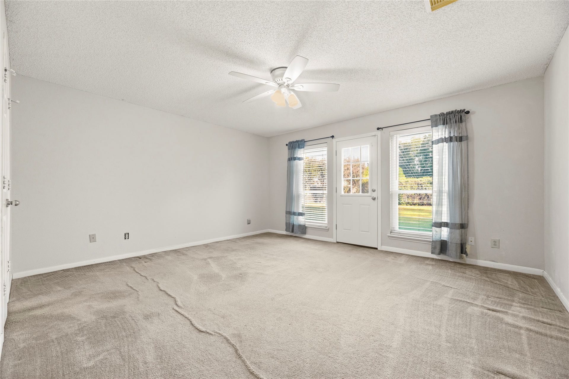 9922 W Cedaredge Drive, Houston, TX 77064 Bright and spacious primary bedroom featuring a ceiling fan and double windows with a door leading to a serene outdoor view.