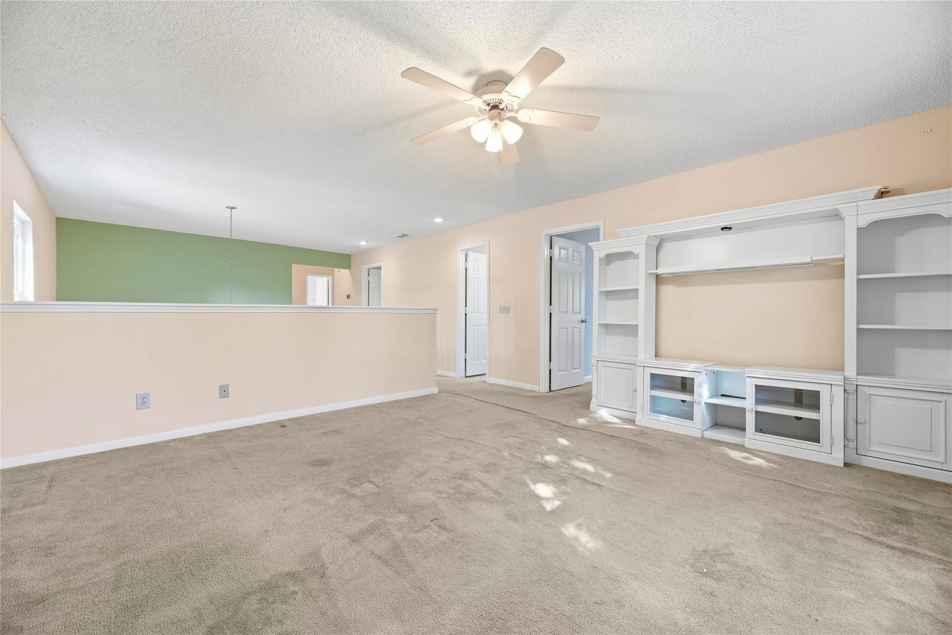 9922 W Cedaredge Drive, Houston, TX 77064 Spacious upstairs living room/game room space featuring a ceiling fan, built-in entertainment unit perfect for relaxation, play and gatherings.