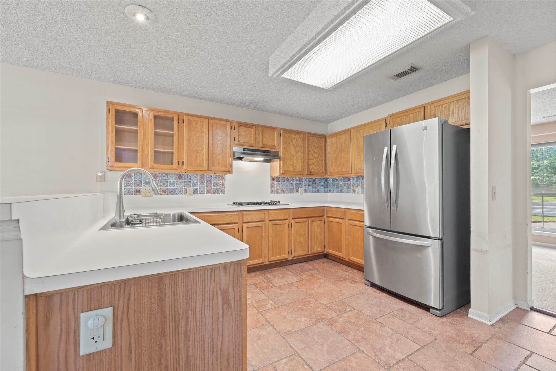9922 W Cedaredge Drive, Houston, TX 77064 Spacious kitchen featuring sleek stainless steel appliances, warm wooden cabinetry, and a charming tile backsplash.