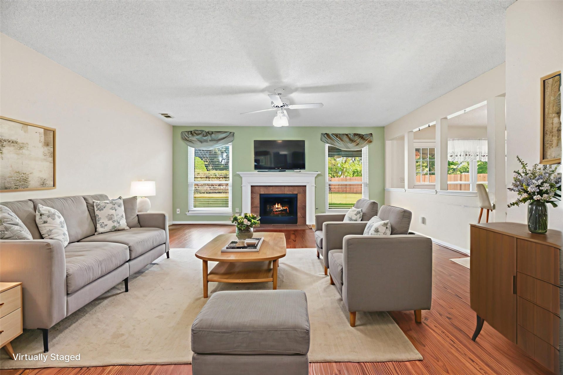 9922 W Cedaredge Drive, Houston, TX 77064 Virtually Staged--Living room offers a cozy fireplace, hardwood floors, and abundant natural light from large windows.