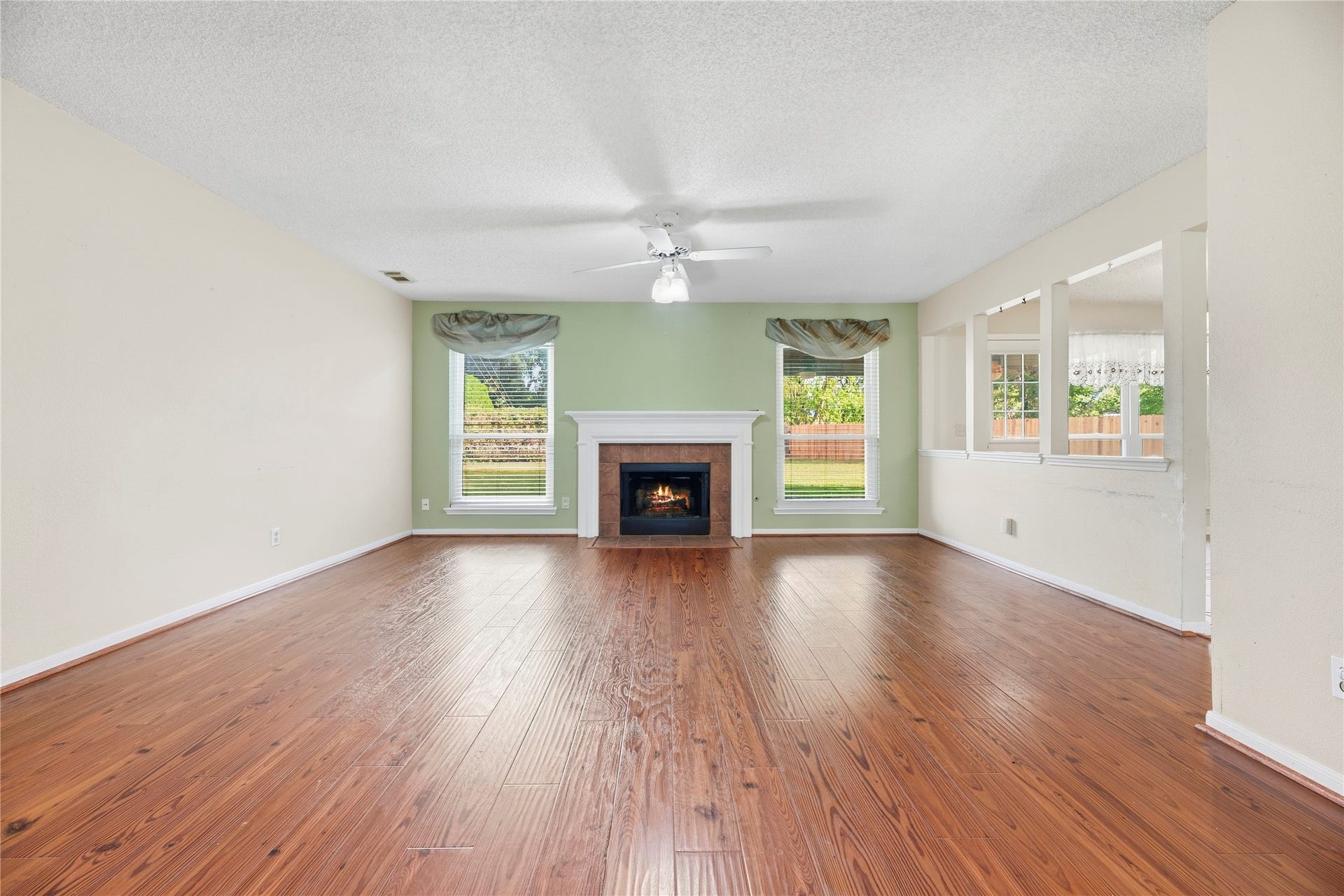 9922 W Cedaredge Drive, Houston, TX 77064 Living room offers a cozy fireplace, hardwood floors, and abundant natural light from large windows.