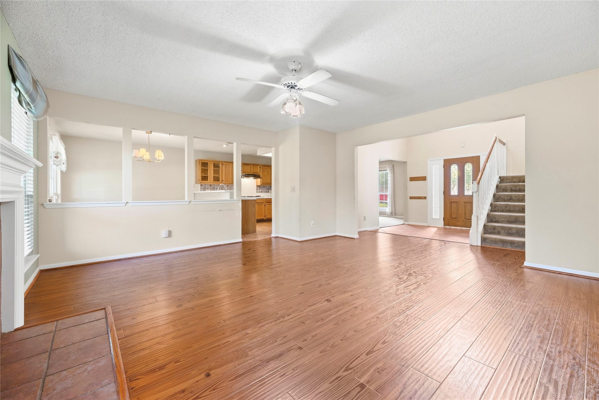 9922 W Cedaredge Drive, Houston, TX 77064 Spacious living area with rich wood flooring, a ceiling fan, and an open layout connecting to the kitchen and breakfast space.