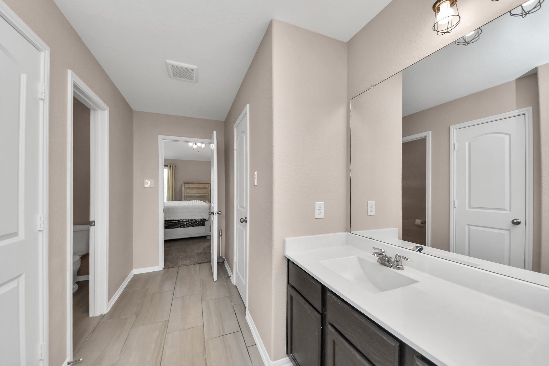 Spacious primary bathroom includes a private water closet and direct access to both the bedroom and second primary closet.