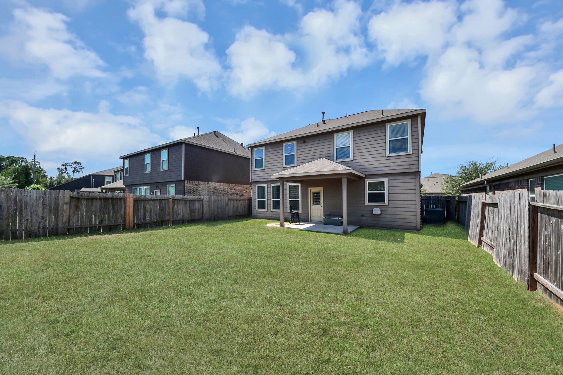 Large backyard features a covered patio for shaded relaxation with abundant open lawn for gatherings, play or future enhancements.