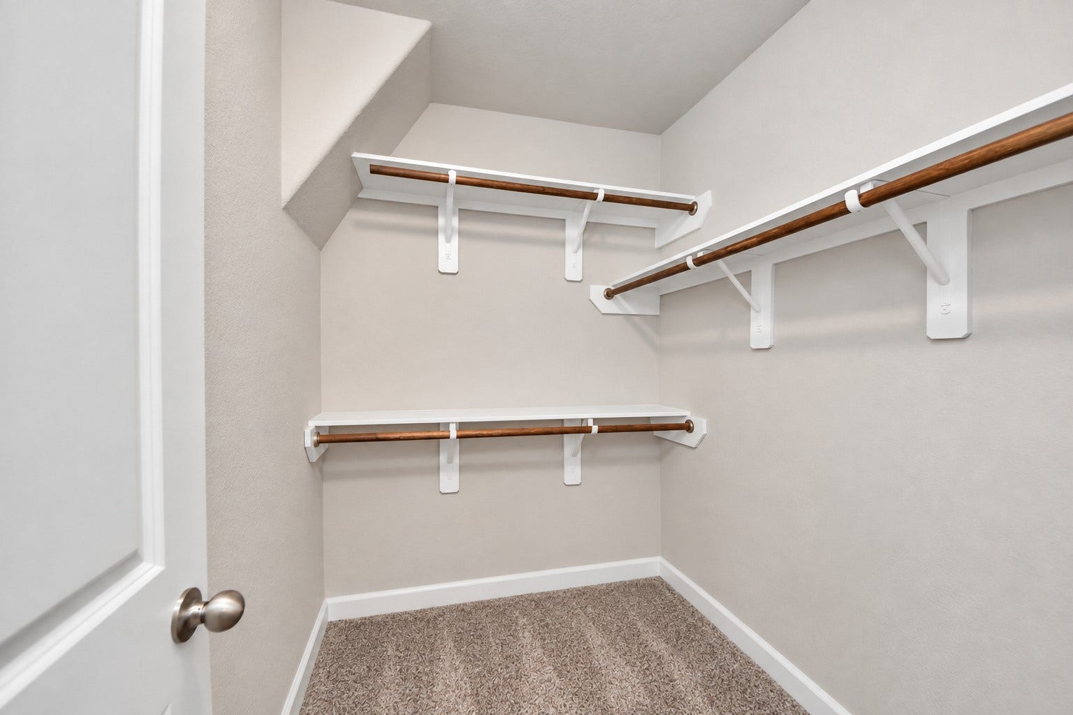 Spacious primary walk-in closet offers abundant hanging space and built-in shelving for organized storage.