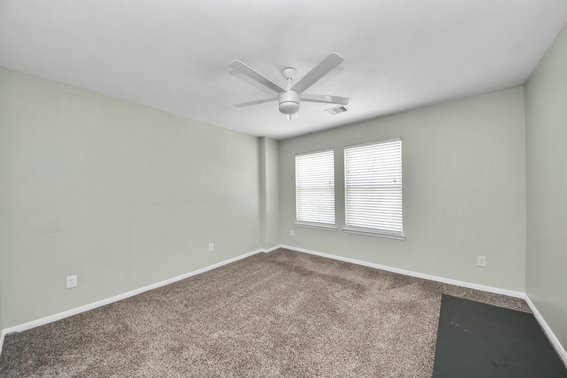 Spacious third bedroom features two windows that fill the room with natural light and plenty of flexibility for guests, work or relaxation.