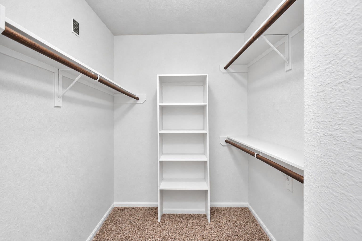 Second primary walk-in closet features multiple hanging rods and built-in shelving for added organization and storage.