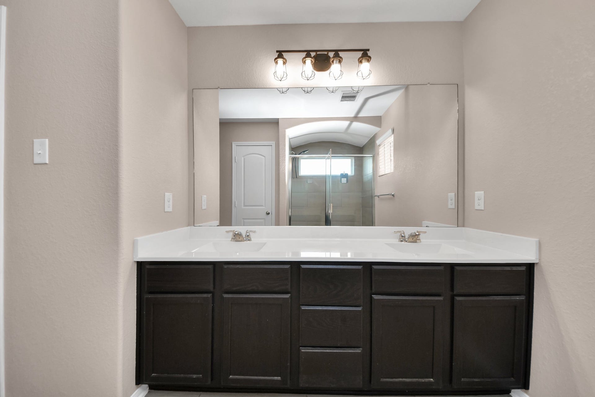 Expansive vanity provides generous counter space, ample storage and a wall-to-wall mirror with stylish lighting.