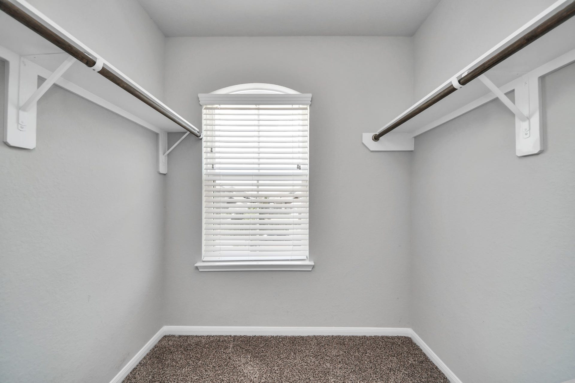 Spacious walk-in closet for the second bedroom features hanging space on both sides and a window for added natural light.