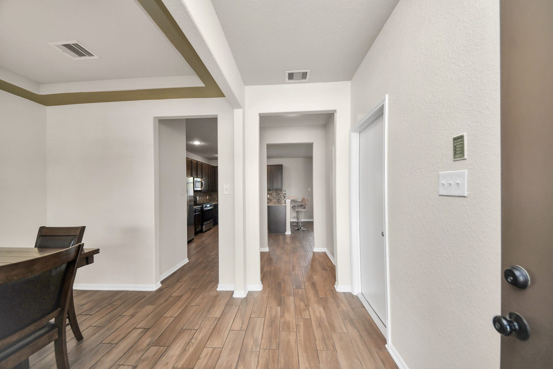 Inviting entryway featuring wood-look tile flooring and an open view into the kitchen and dining areas.