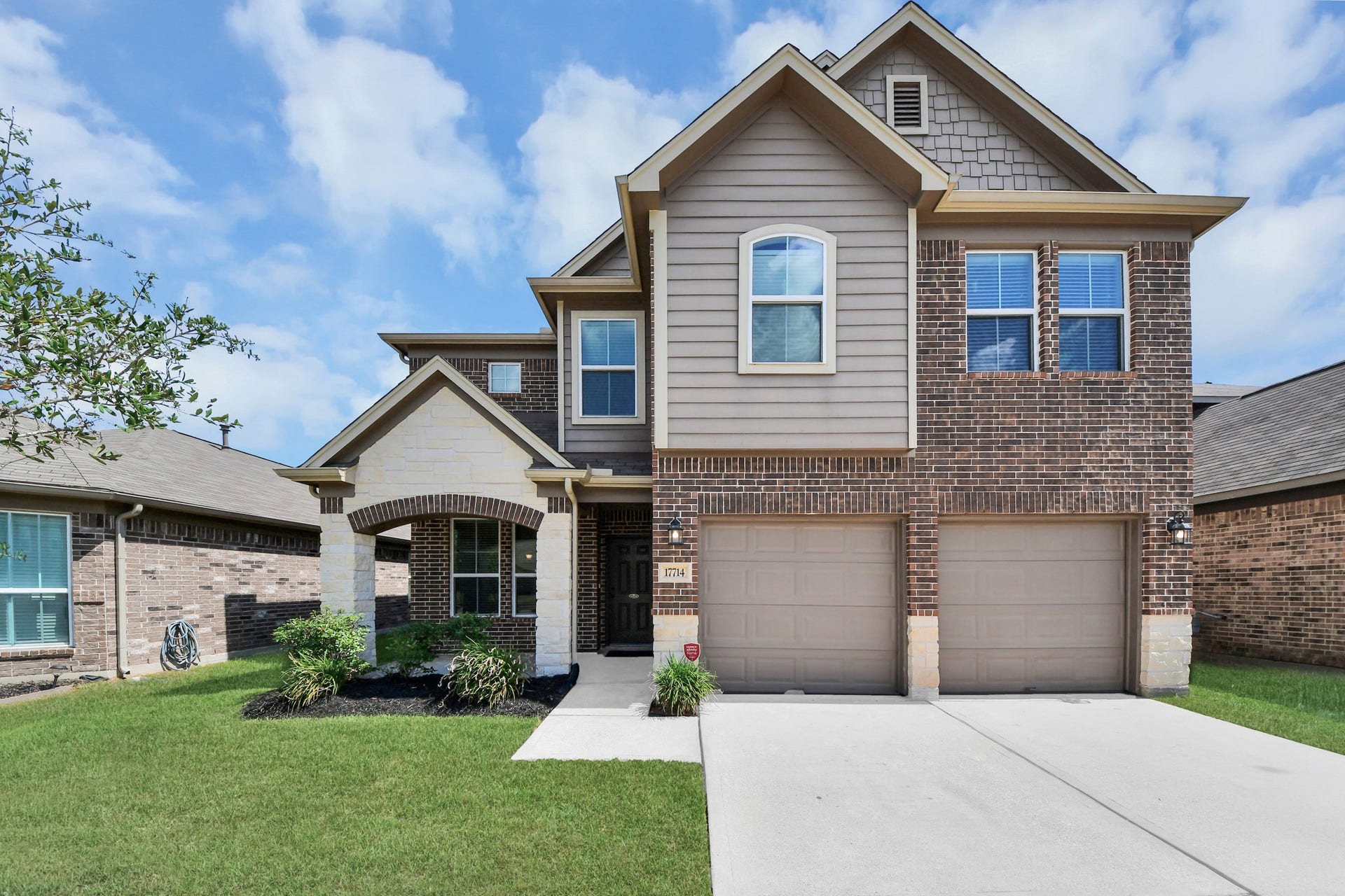 Beautiful two-story home featuring a stunning brick-and-stone exterior, manicured front lawn and attached two-car garage.