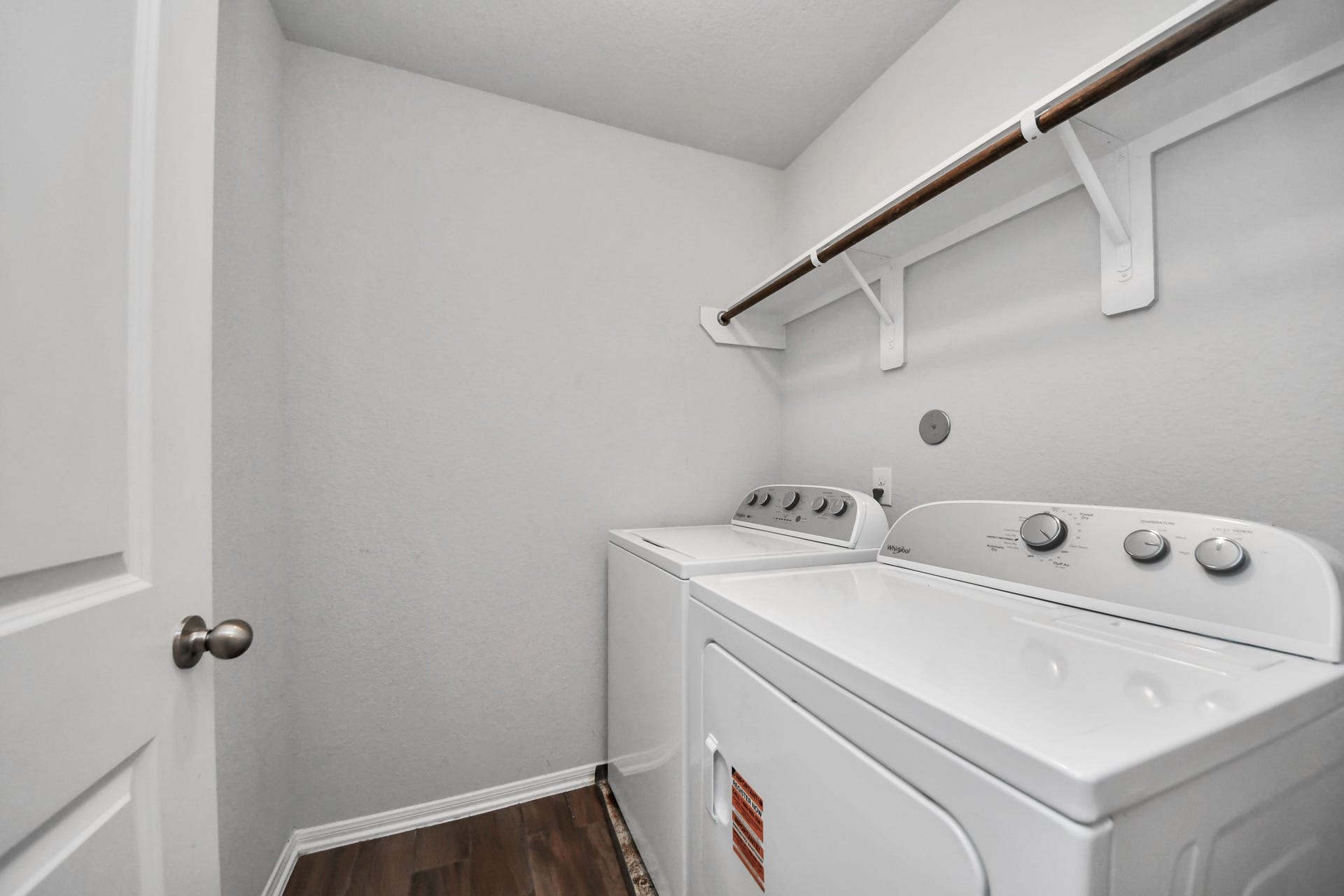 Convenient upstairs laundry room includes the washer and dryer, plus built-in shelving and hanging space.