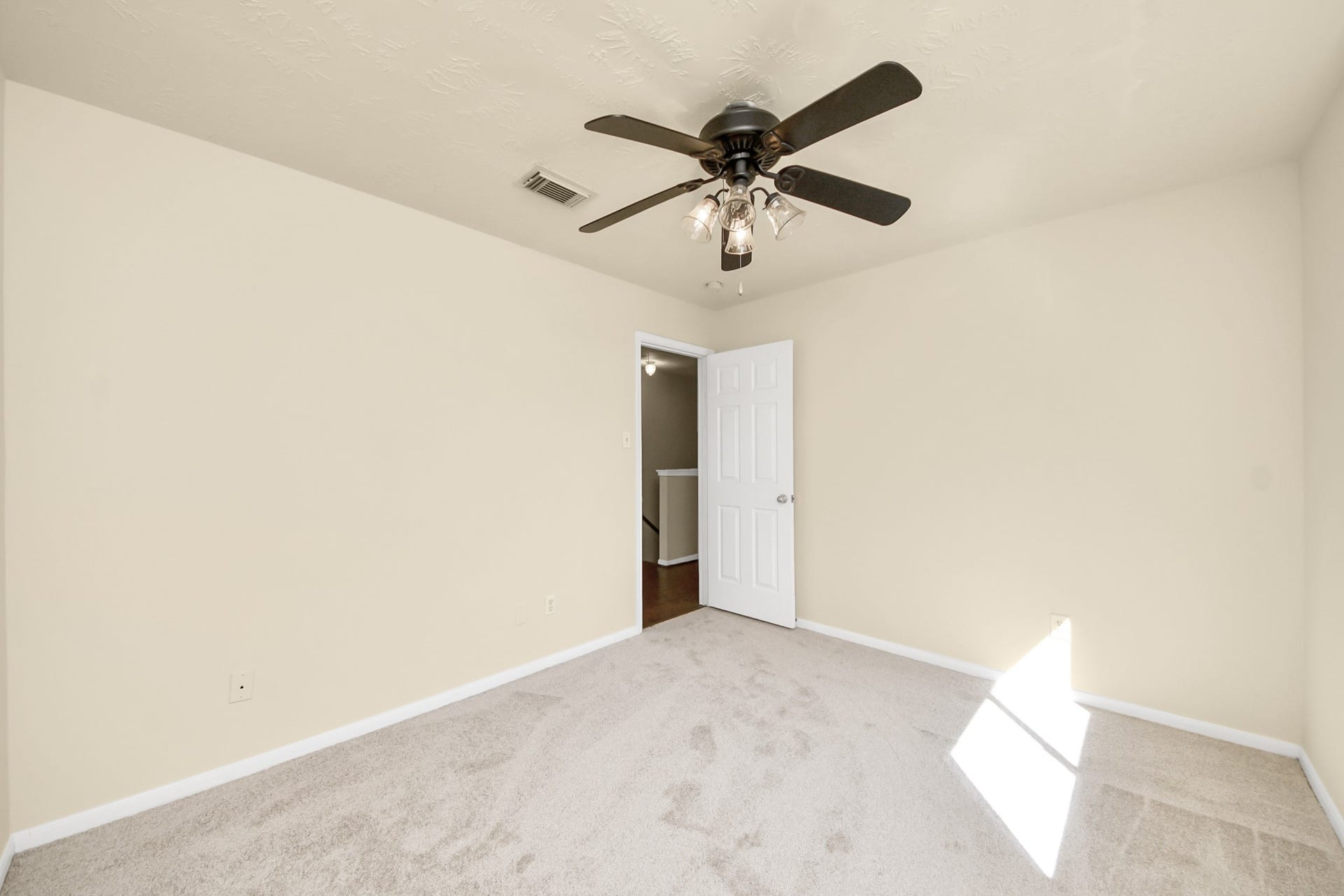 Bright and airy bedroom featuring neutral walls, brand new carpet, and ceiling fan.