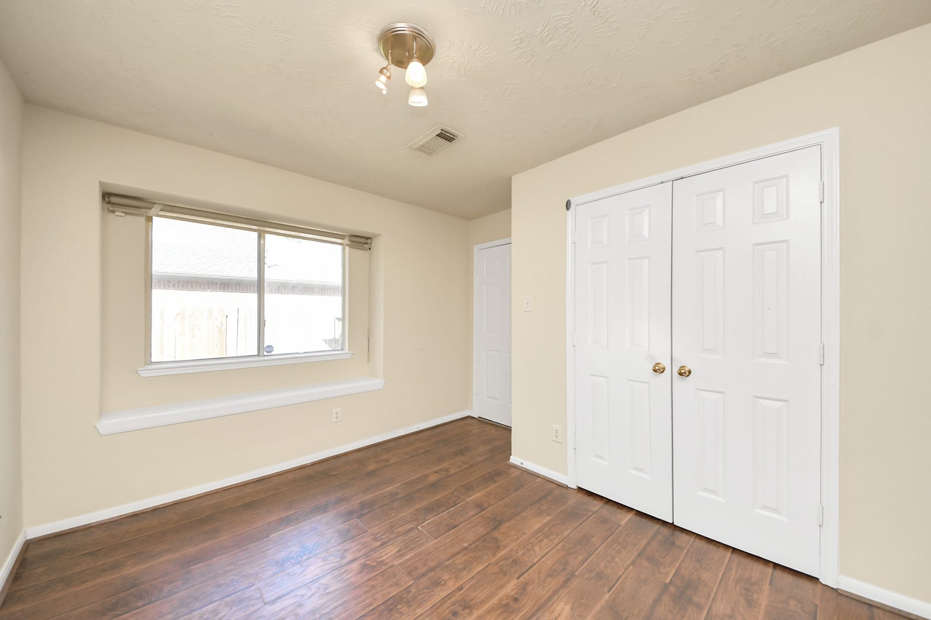 Bright breakfast room with hardwood floors, double pantry, and a large window offering natural light. Door leading to garage access.