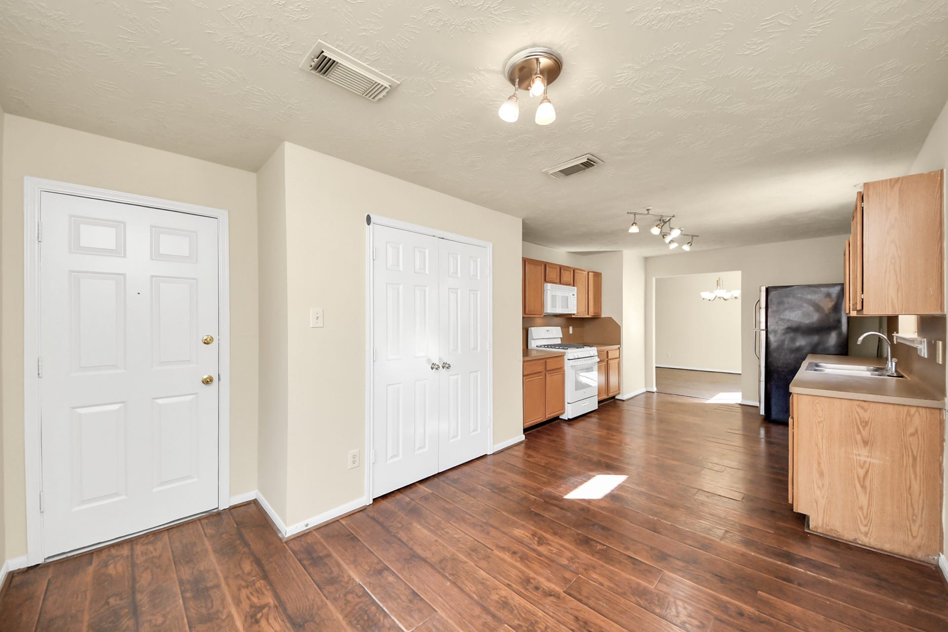 Warm wood flooring, double pantry and appliances, leading into an open dining area.