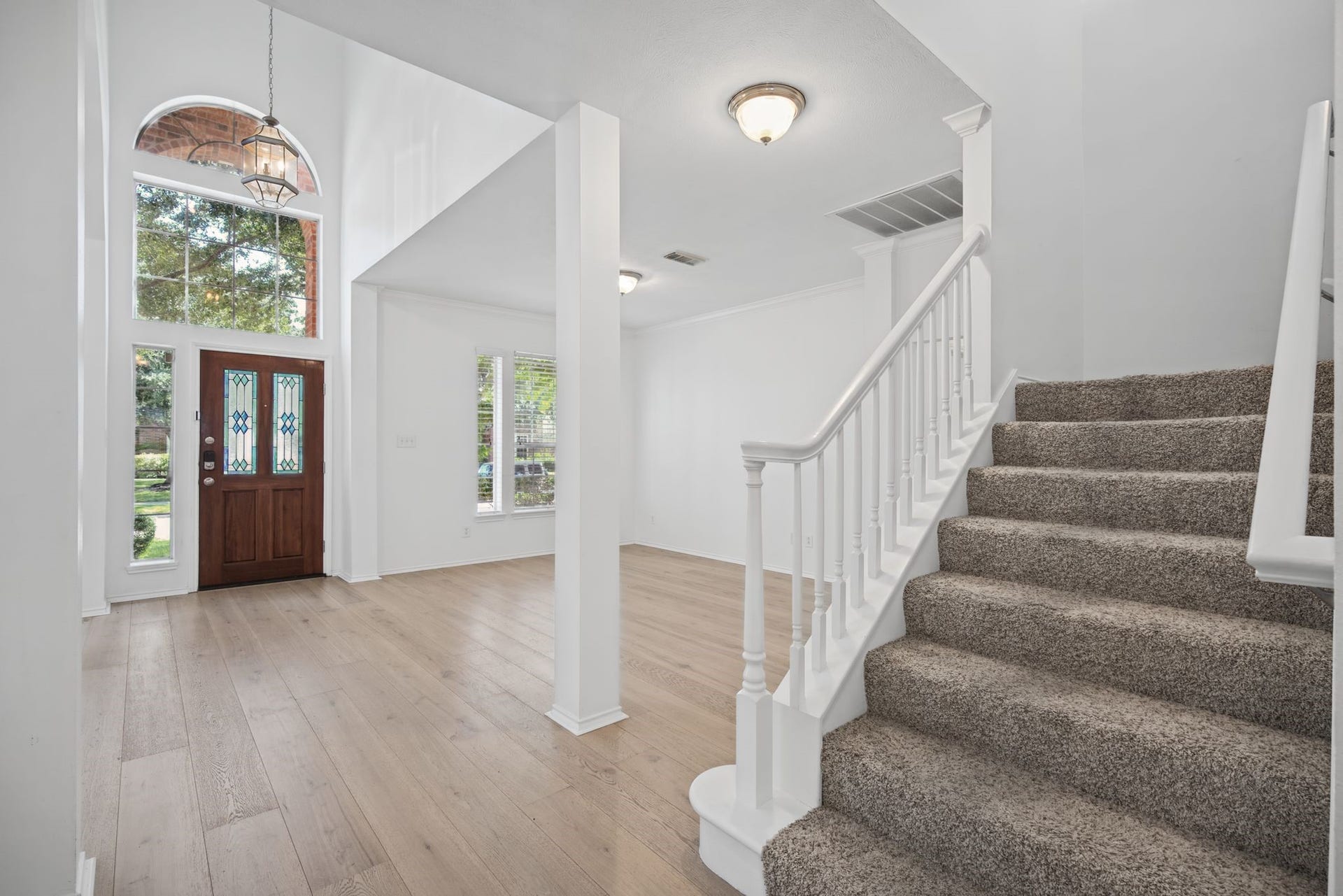 Step inside to a light-filled entry with soaring ceilings, light-toned flooring, and a staircase finished with crisp white railings.