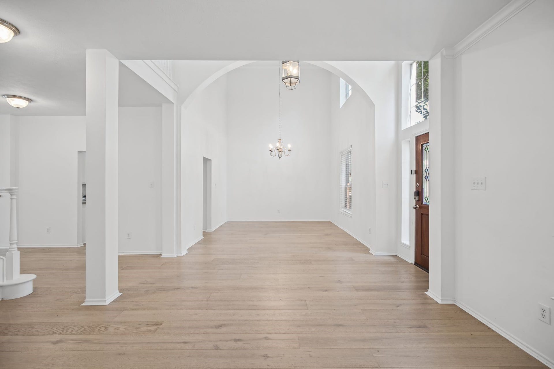 The entry introduces an inviting arrangement of formal living and dining spaces, connected by a sweeping arched opening.