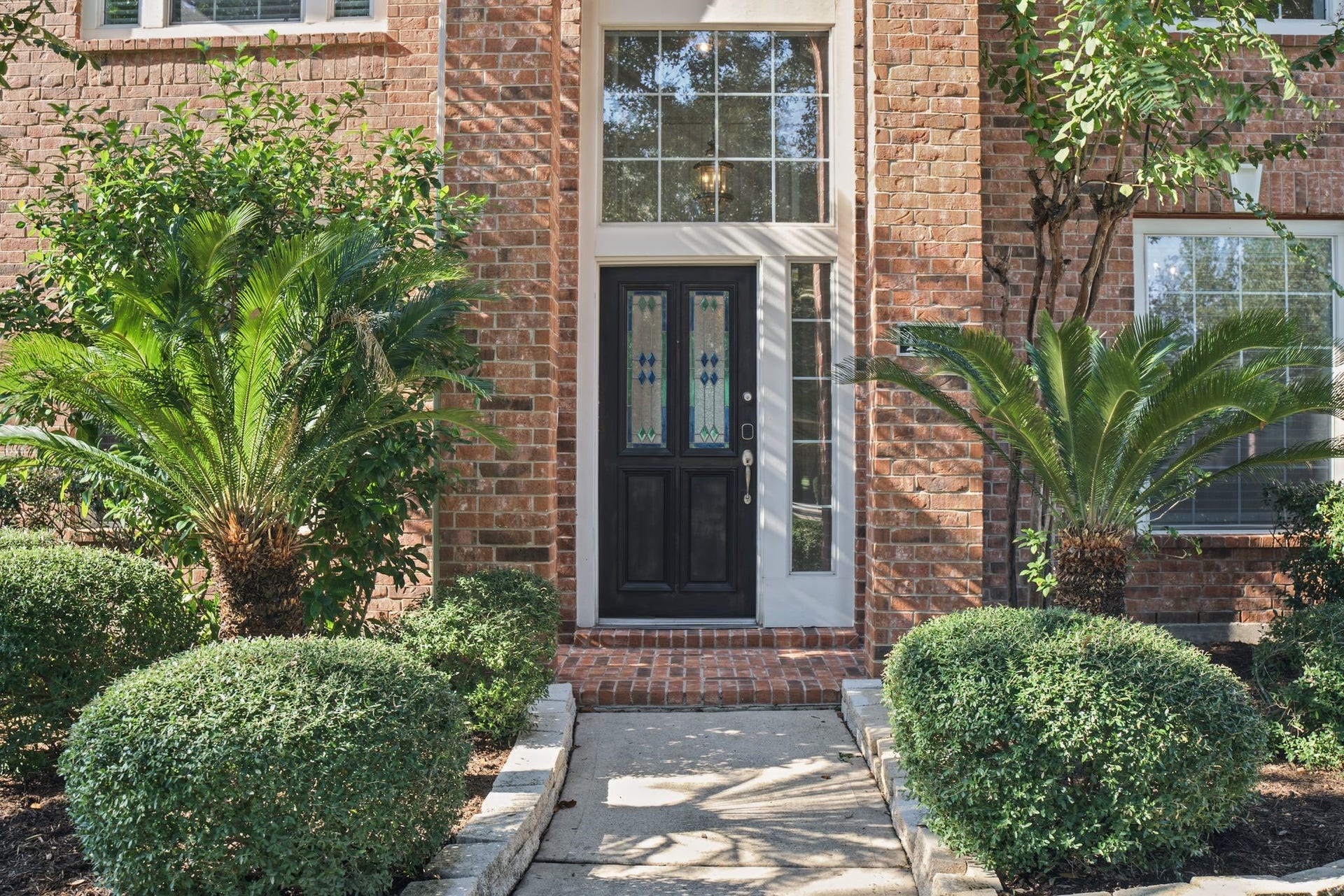 Approach the front entrance, where decorative glass, sidelights, and a tall overhead window offer a warm welcome.