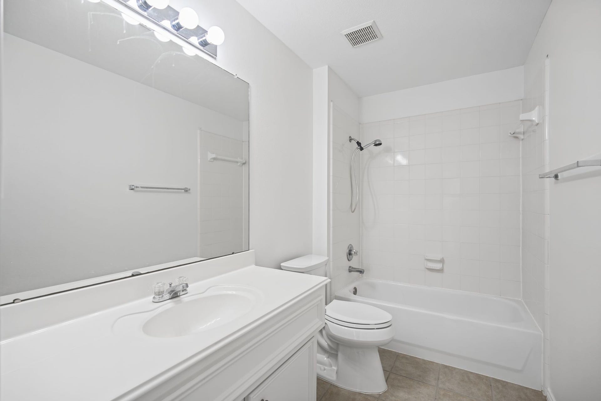 Another view highlights the tiled tub-and-shower surround and the vanitys counter space.