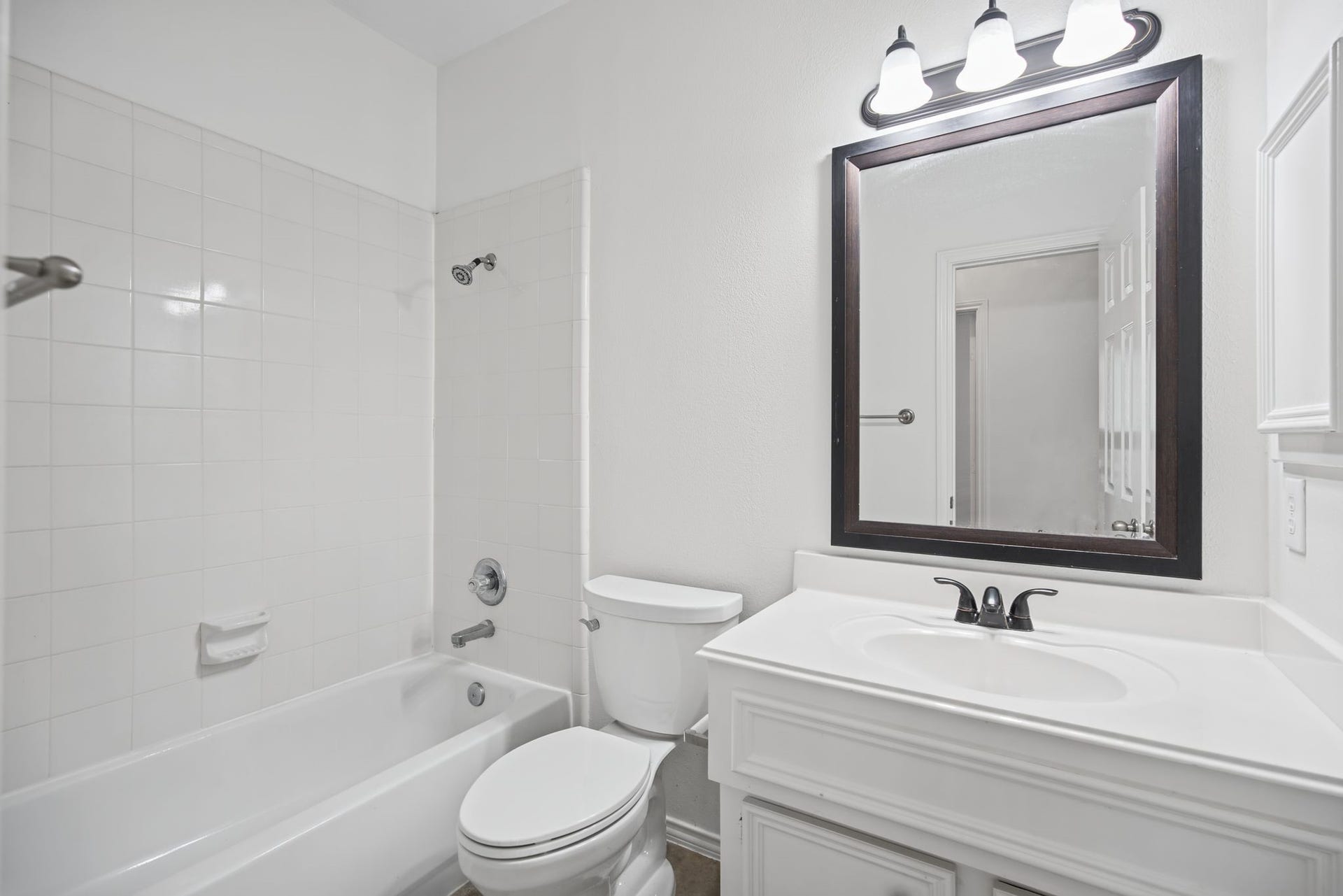 The first-floor bathroom features a white vanity, framed mirror, and a tub-and-shower combination with a tiled surround.
