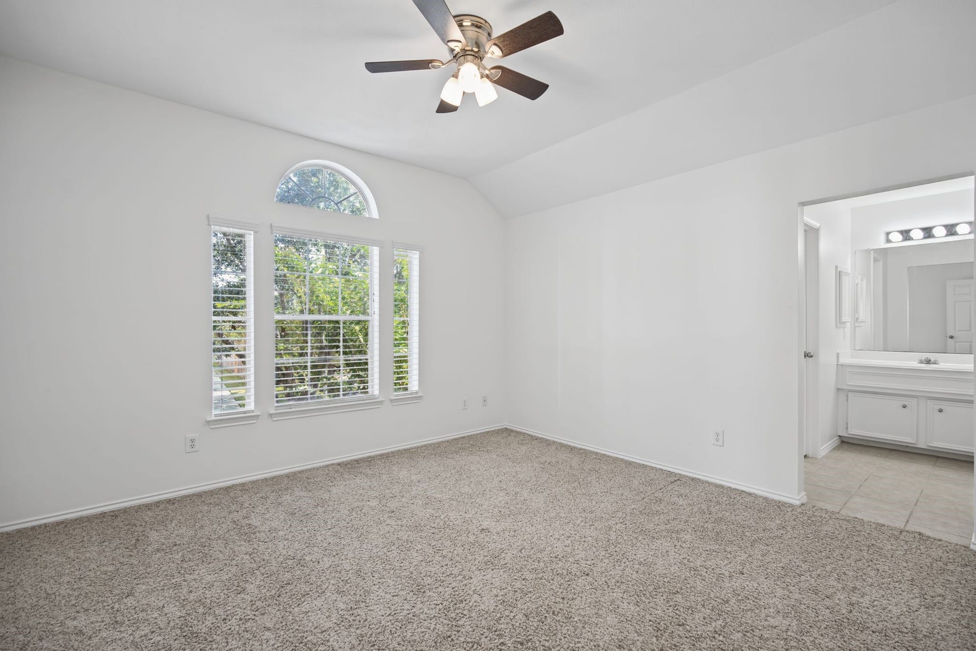 An additional bedroom welcomes natural light through a distinctive window arrangement crowned by an arch.
