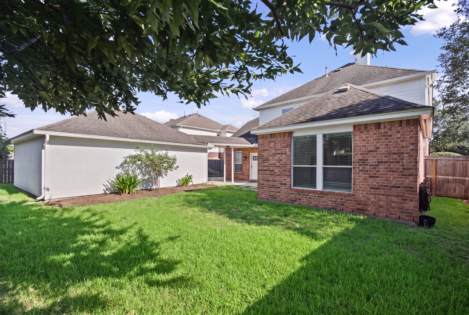 From the lawn, the rear brick exterior and broad windows offer another view of the homes architectural character.