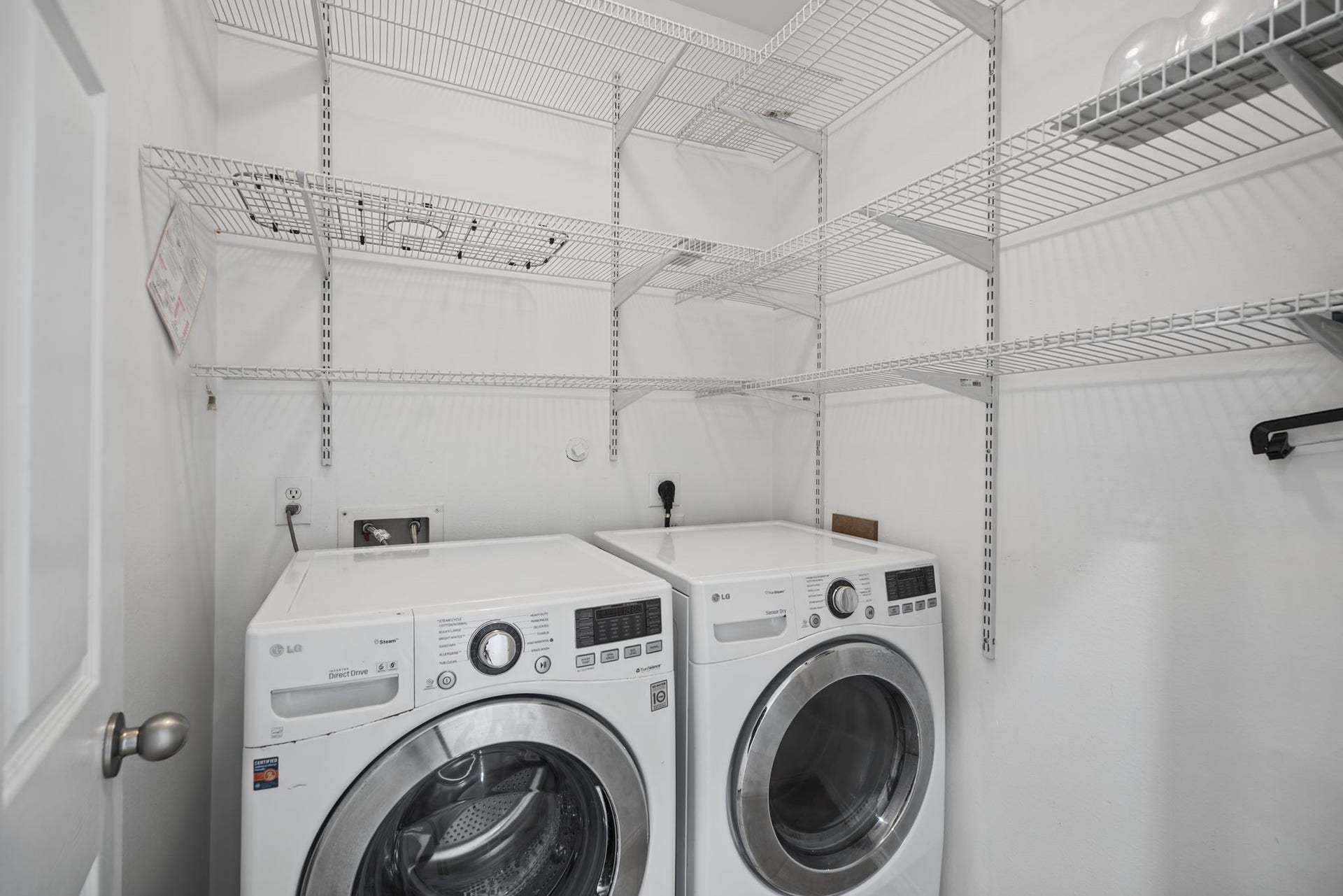 The laundry area brings everyday convenience into focus, with shelving above and around the washer and dryer.
