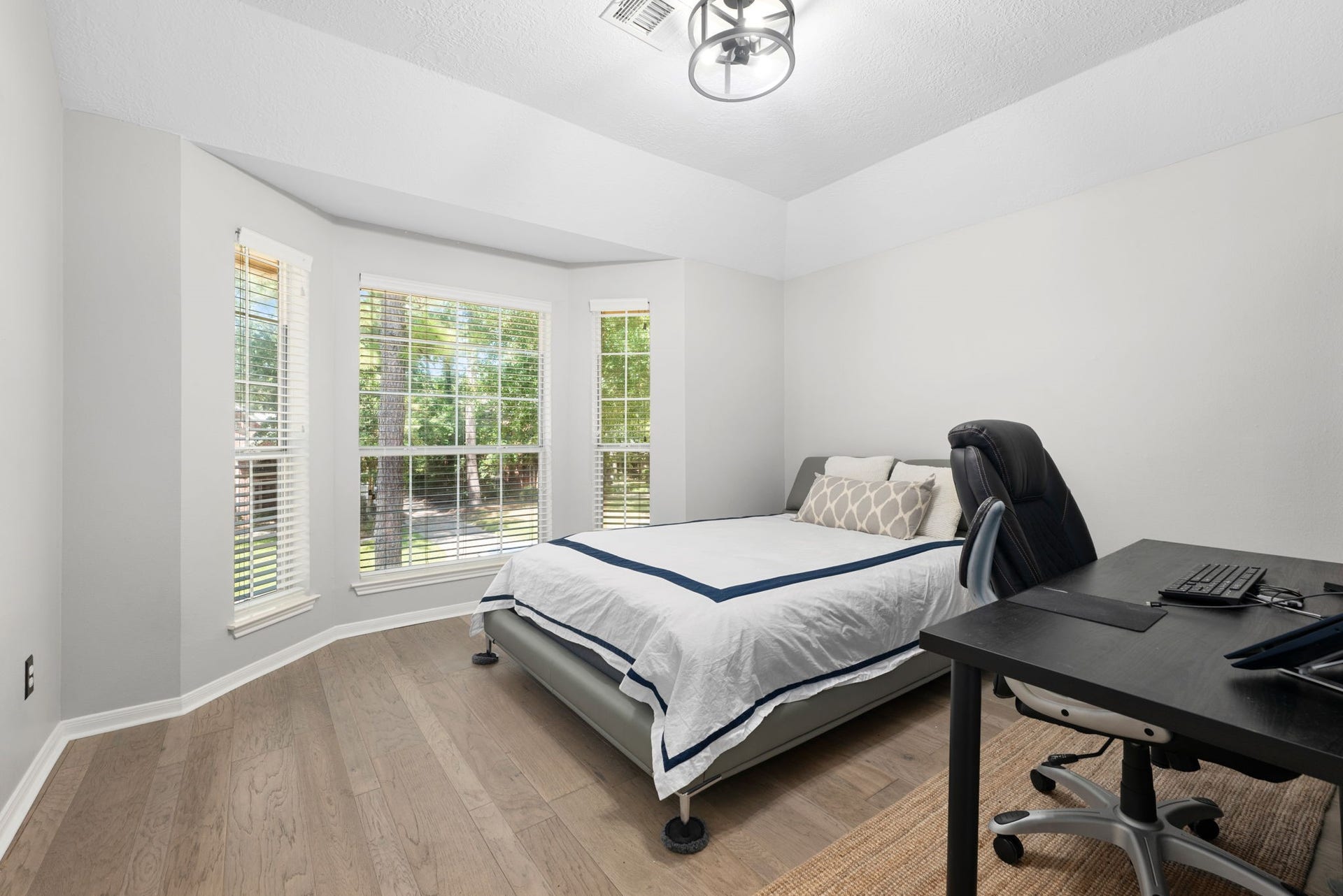 Bright and inviting secondary bedroom with a spacious bay window, elegant wood flooring.