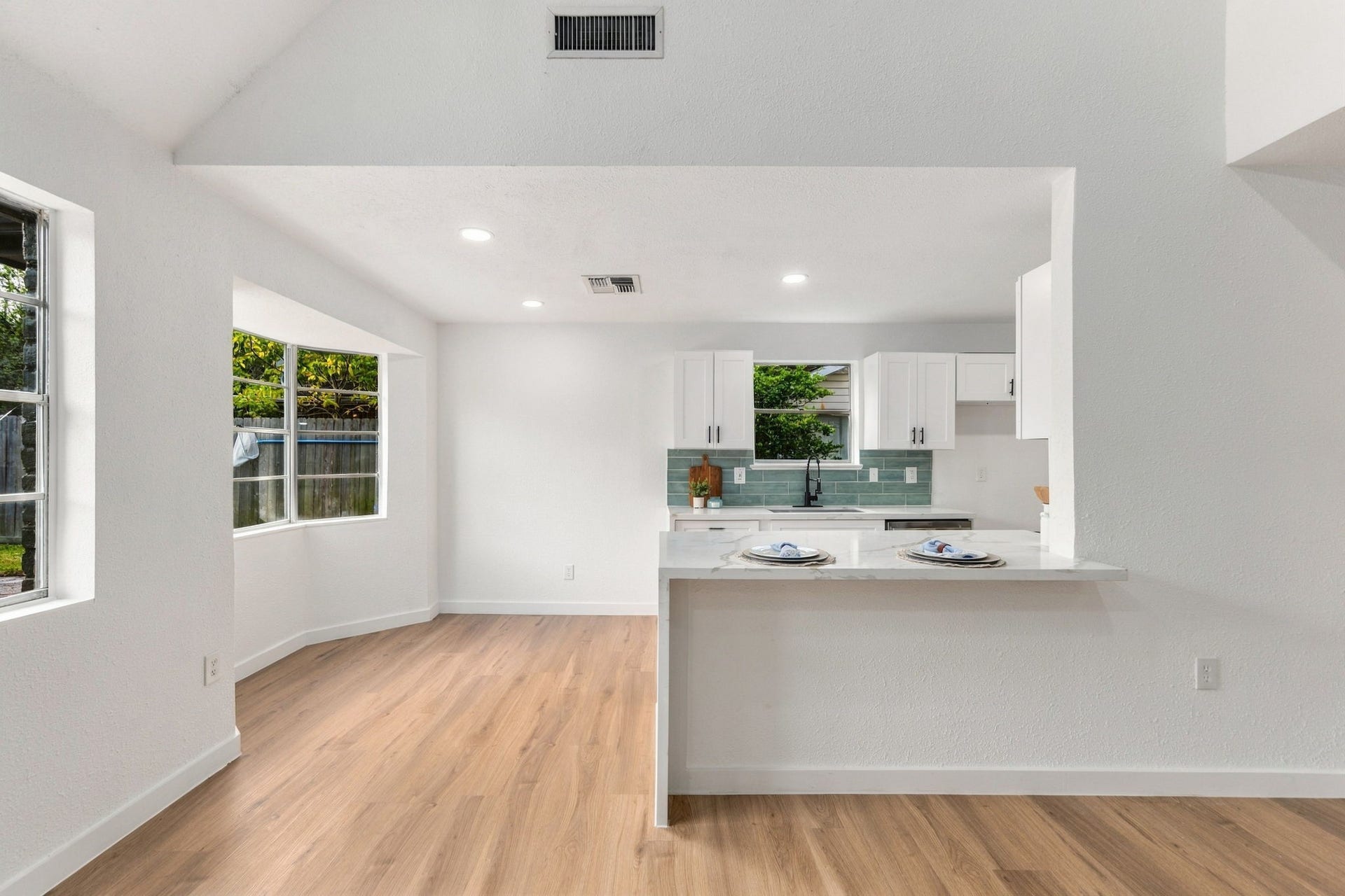 Custom white cabinetry offers a clean, timeless look with ample storage, while the spacious breakfast bar offers the perfect spot for casual dining or entertaining.