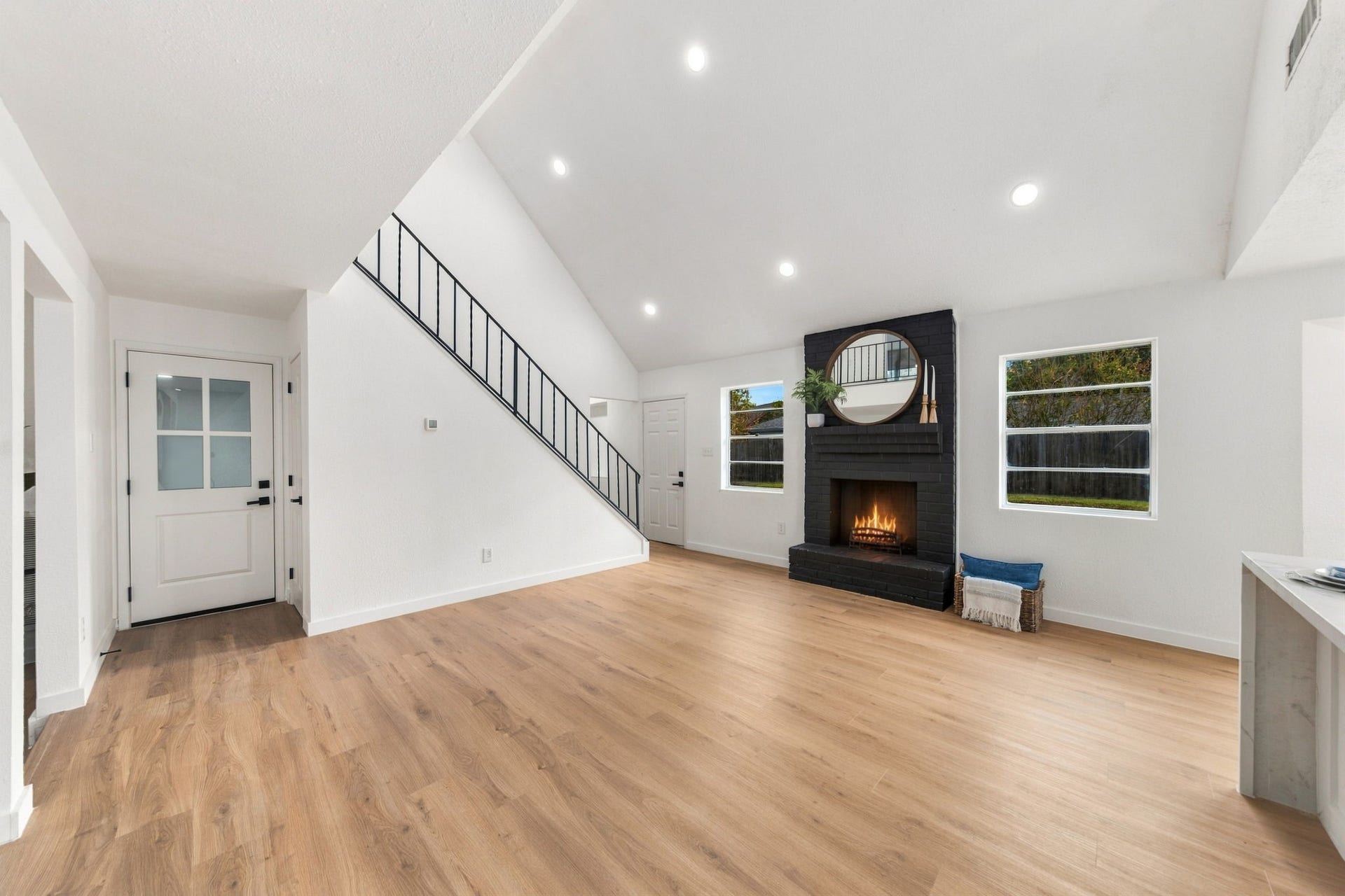 Main living area showcases the beautifully updated painted brick fireplace and the striking staircase.