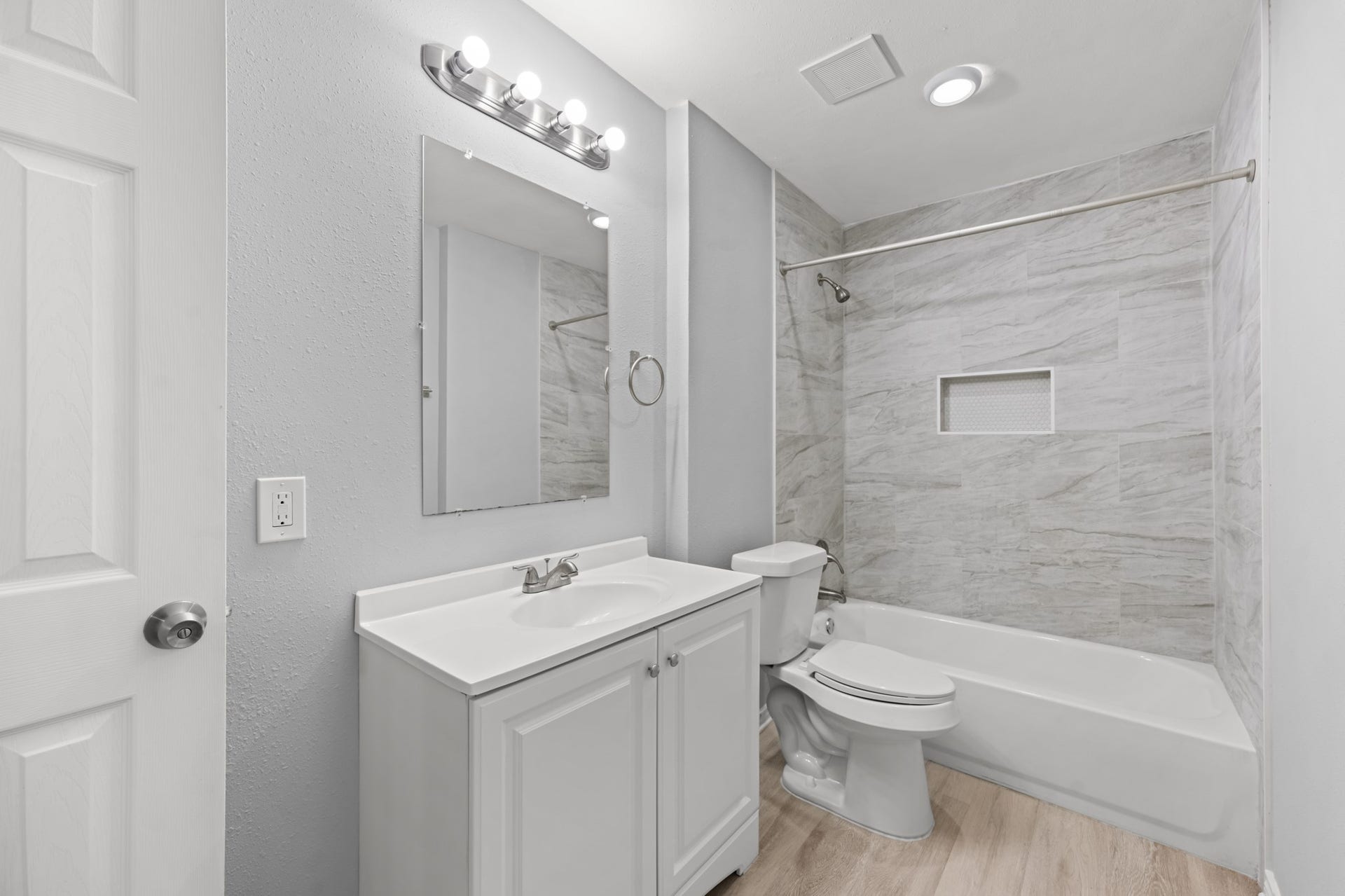 4802 Hannas Reef Drive, Bacliff, TX 77518 The updated guest bathroom features a white vanity, modern lighting, and a tub/shower combination with beautiful marble-look tile surround and a convenient recessed shower niche.