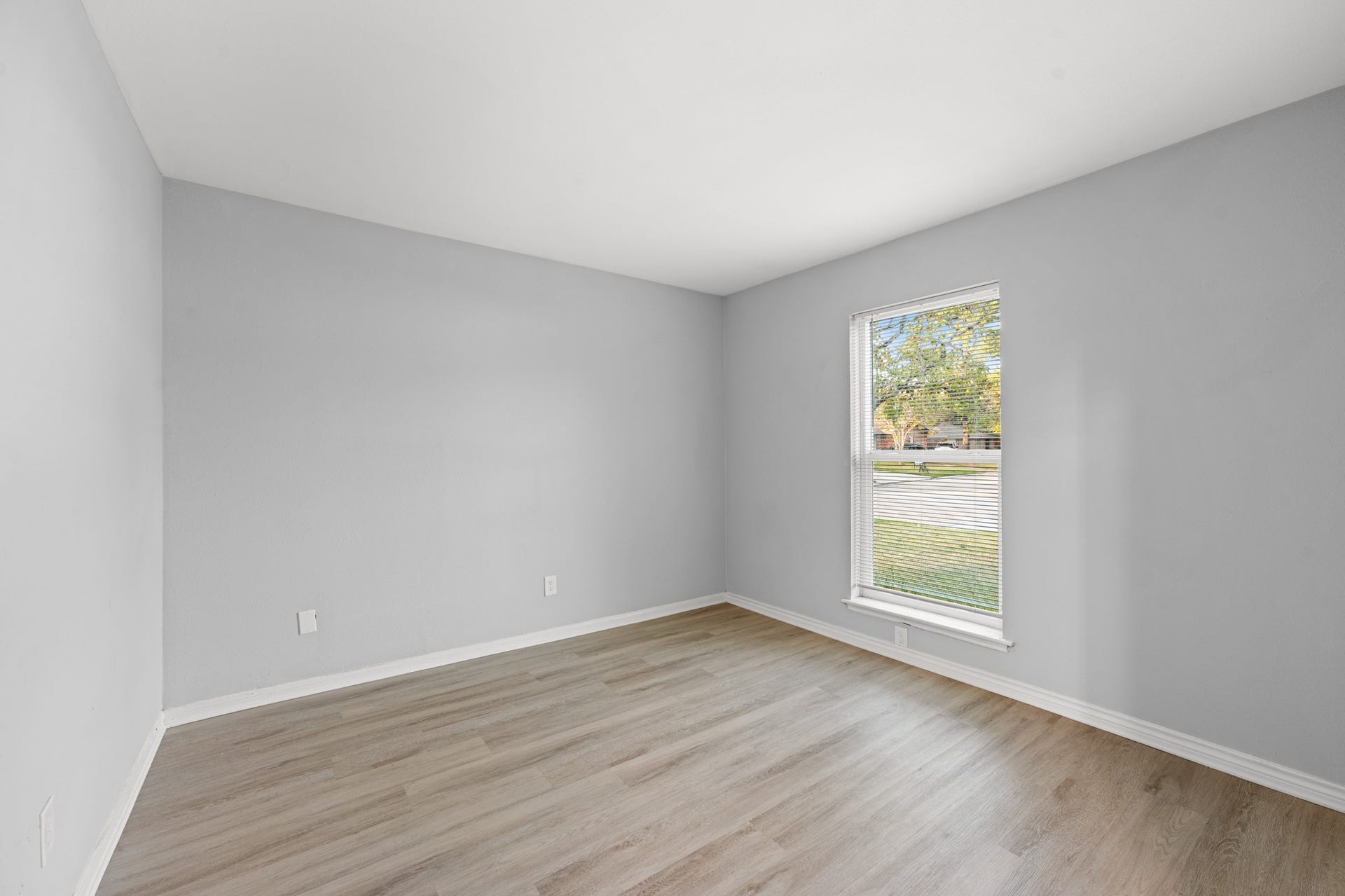 4802 Hannas Reef Drive, Bacliff, TX 77518 A bright, versatile home office features wood-look flooring, neutral gray walls, and a large window overlooking the front yard, creating an inviting space for working from home.