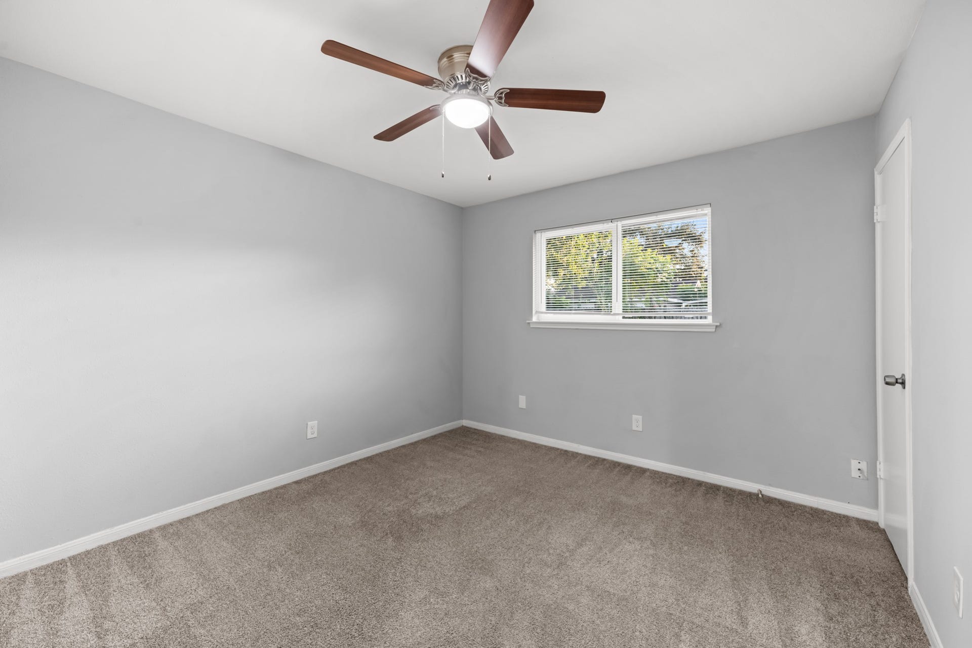 4802 Hannas Reef Drive, Bacliff, TX 77518 This comfortable additional bedroom offers plush carpeting, neutral gray walls, a ceiling fan with integrated lighting, and a window overlooking the outdoors.