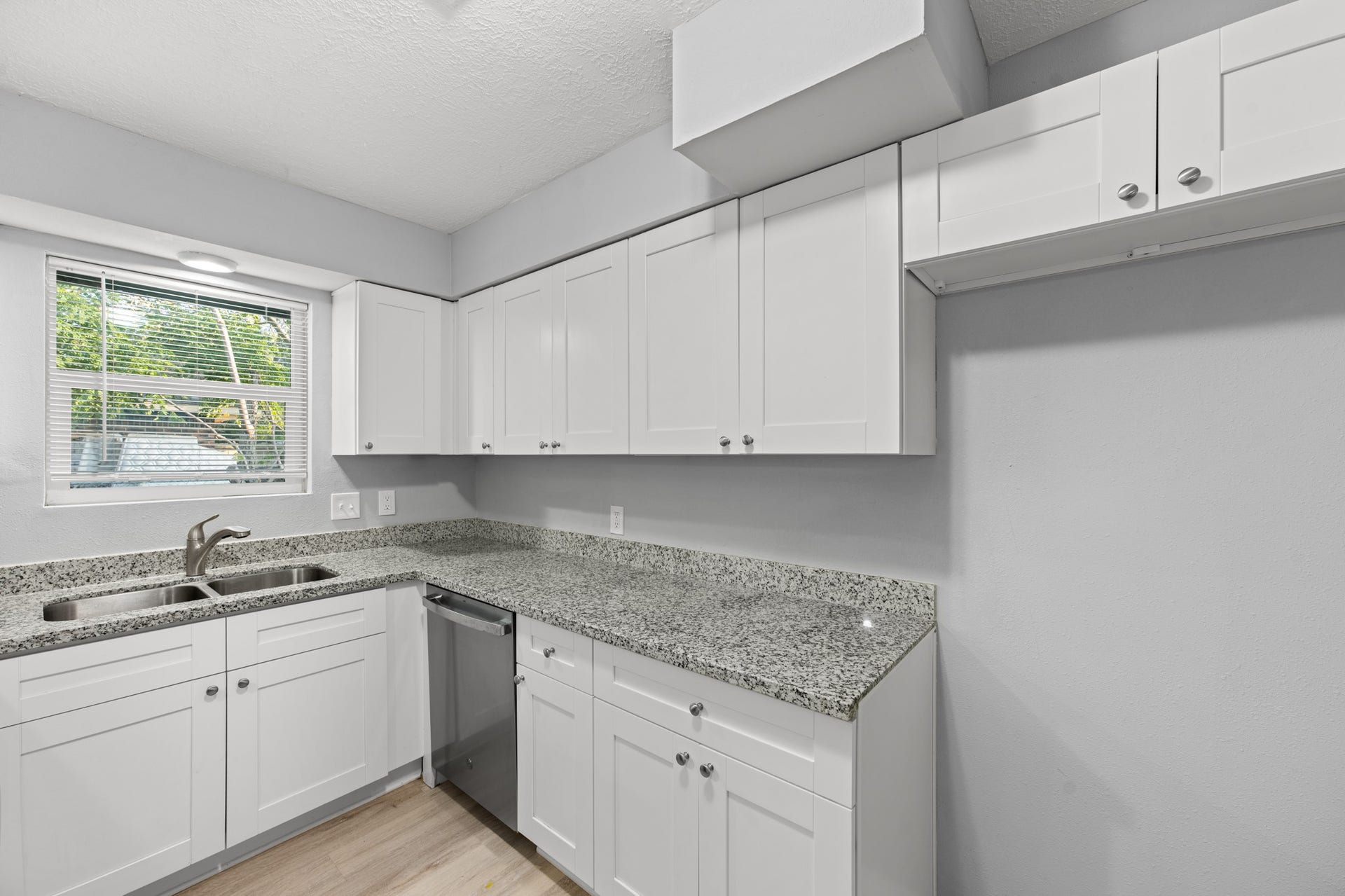 4802 Hannas Reef Drive, Bacliff, TX 77518 Expansive granite countertops provide plenty of room for meal preparation, complemented by white shaker-style cabinetry, a stainless steel dishwasher, and a double-basin sink overlooking the outdoors.