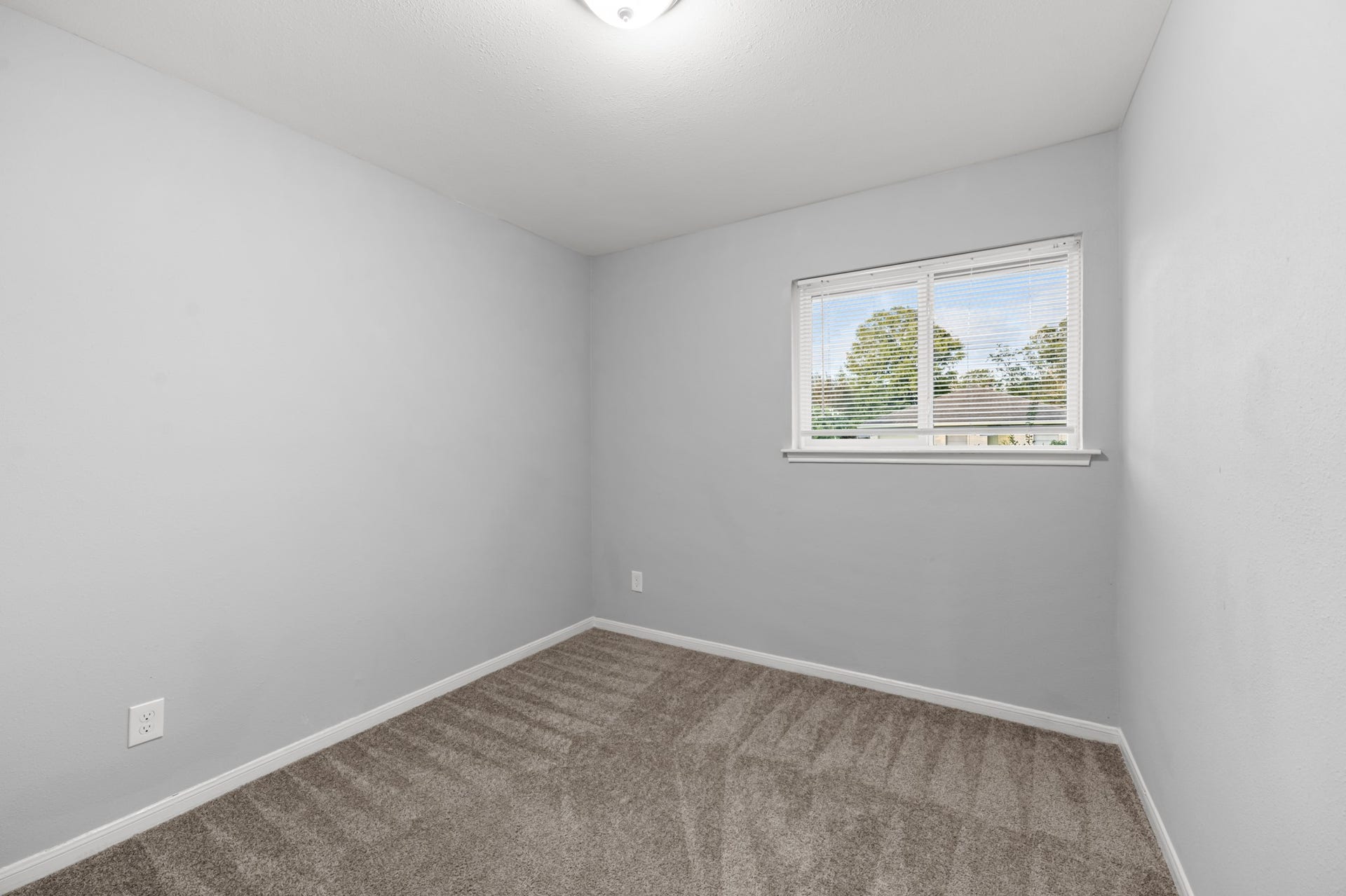 4802 Hannas Reef Drive, Bacliff, TX 77518 This inviting secondary bedroom features soft neutral wall colors, plush carpeting, and a window that welcomes natural light, creating a comfortable and versatile space.