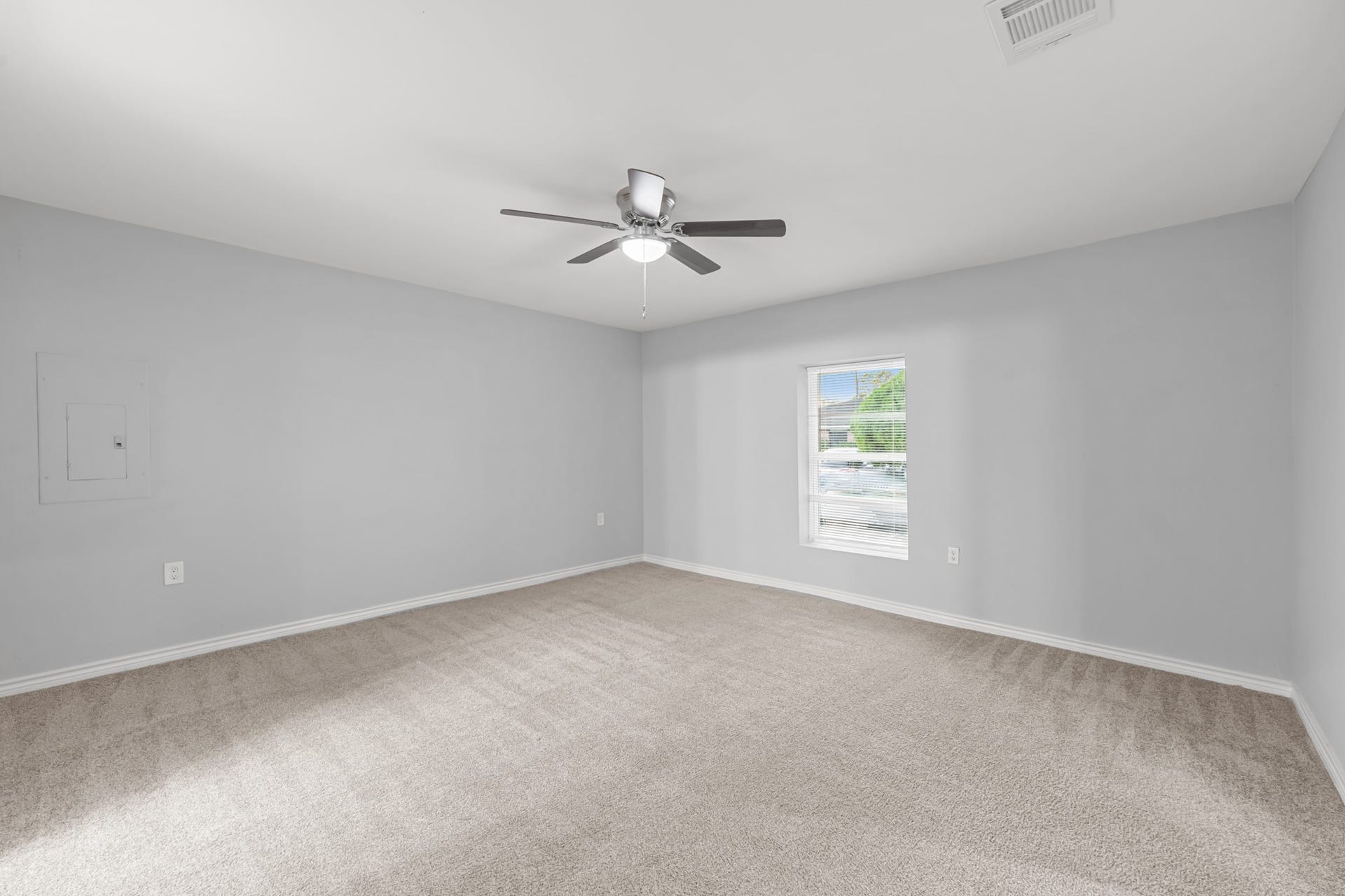 4802 Hannas Reef Drive, Bacliff, TX 77518 The spacious primary bedroom offers plush neutral carpeting, soft gray walls, a ceiling fan with lighting, and a window that welcomes natural light into the room.