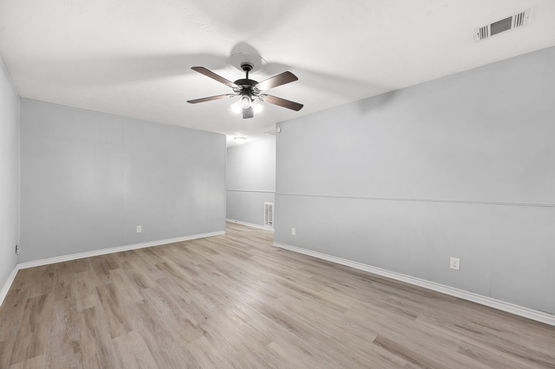 4802 Hannas Reef Drive, Bacliff, TX 77518 This generously sized living area features ample wall space for furniture arrangements, attractive wood-look flooring, and a ceiling fan with integrated lighting.