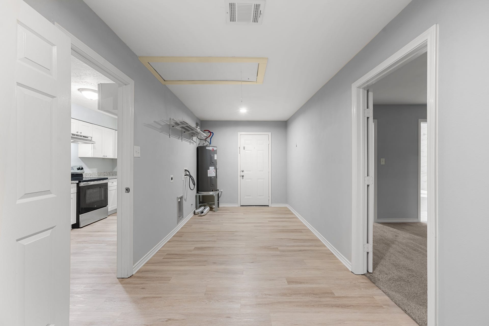 4802 Hannas Reef Drive, Bacliff, TX 77518 Spacious utility room with wood-look flooring, washer and dryer connections, overhead storage shelving, and convenient access to the kitchen and adjoining rooms.