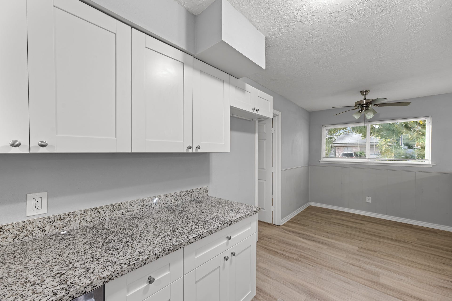 4802 Hannas Reef Drive, Bacliff, TX 77518 The kitchen's extended granite countertop provides additional workspace and storage, while the adjoining dining area features a large window, ceiling fan, and classic wainscoting.