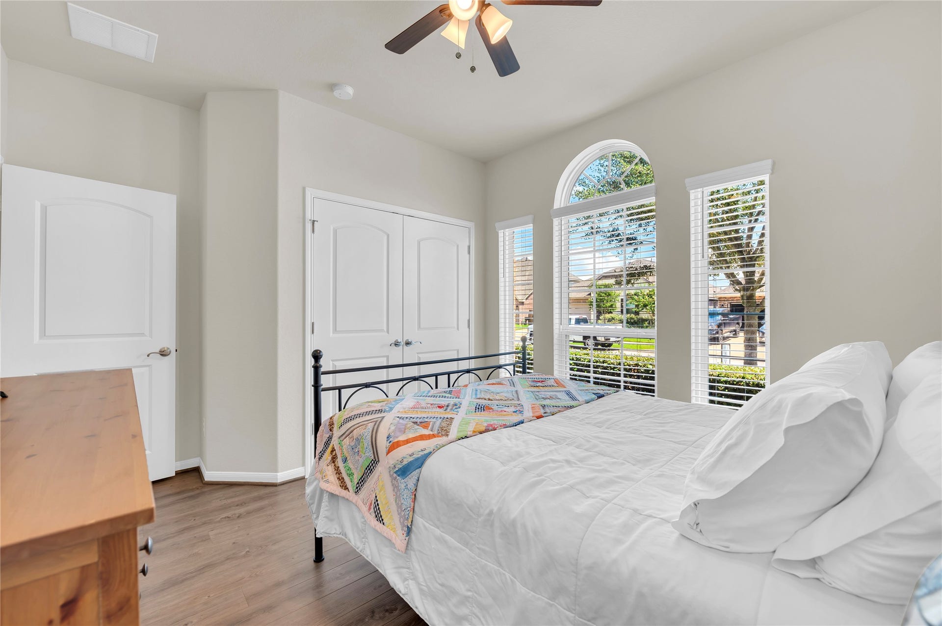 1849 Kenley Way, Alvin, TX 77511 Bright and cozy bedroom featuring large arched windows that let in abundant natural light, complemented by elegant hardwood floors and a spacious closet.