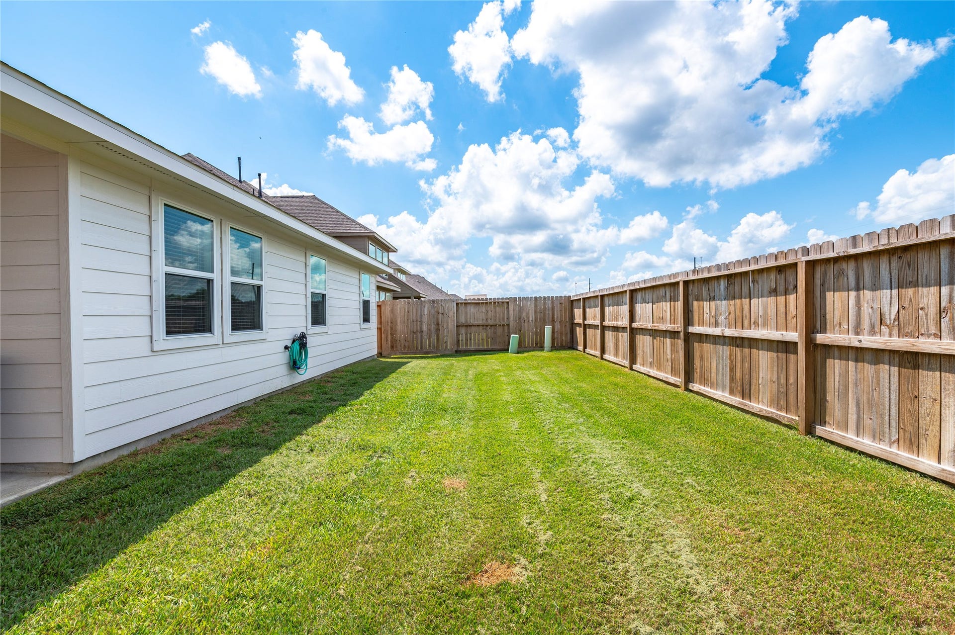 1849 Kenley Way, Alvin, TX 77511 Spacious backyard with a well-maintained lawn, bordered by a new wooden privacy fence, perfect for outdoor activities and relaxation.