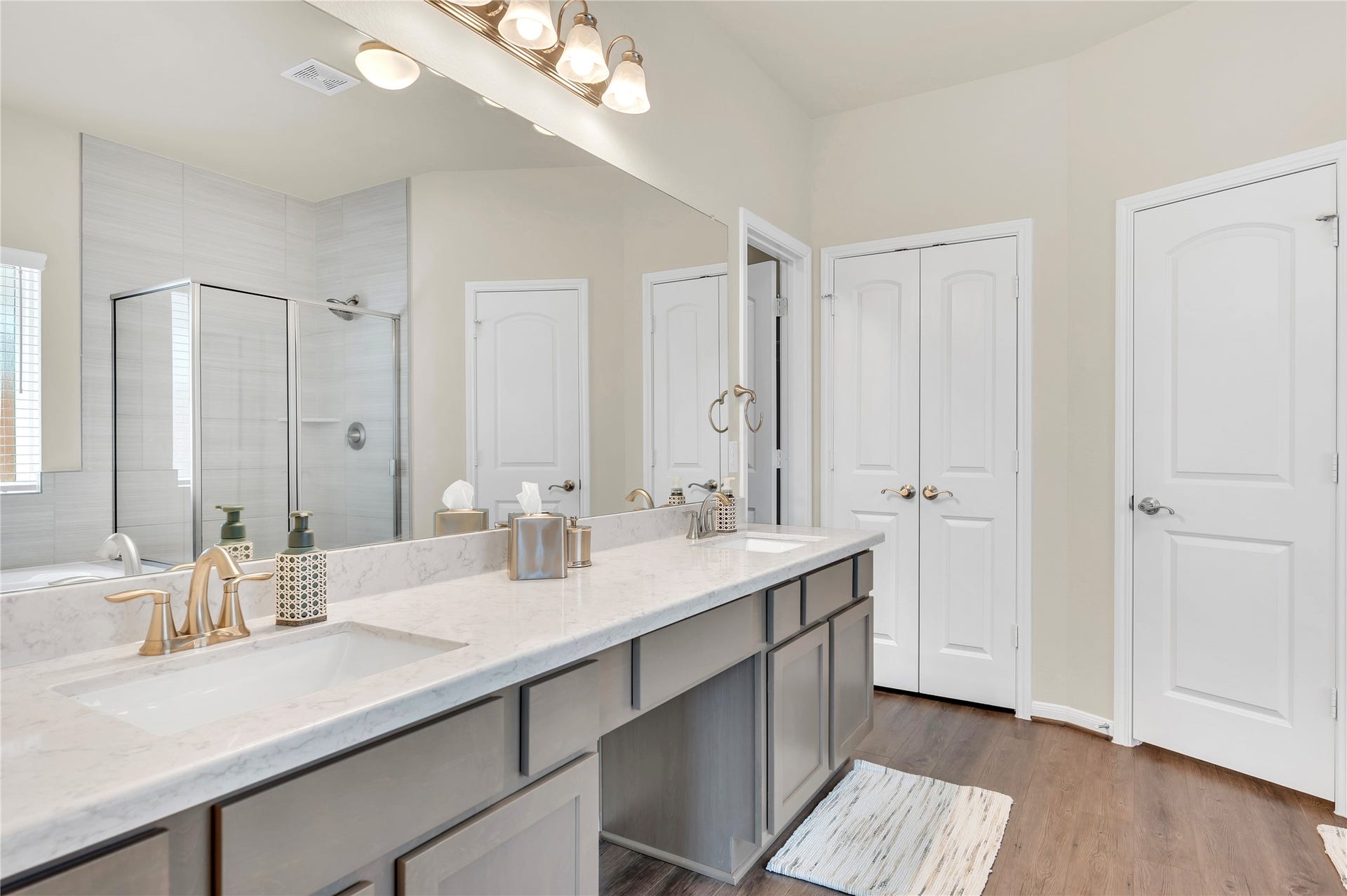 1849 Kenley Way, Alvin, TX 77511 Elegant bathroom featuring a double vanity with marble countertops, modern fixtures, a glass-enclosed shower, and ample storage behind stylish cabinetry.