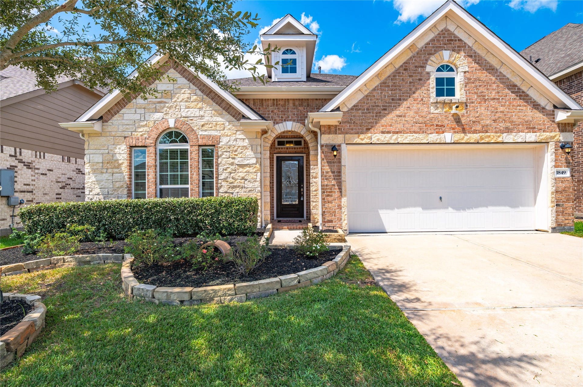 1849 Kenley Way, Alvin, TX 77511 Charming brick and stone home with manicured landscaping, arched windows, and a spacious two-car garage, offering great curb appeal.