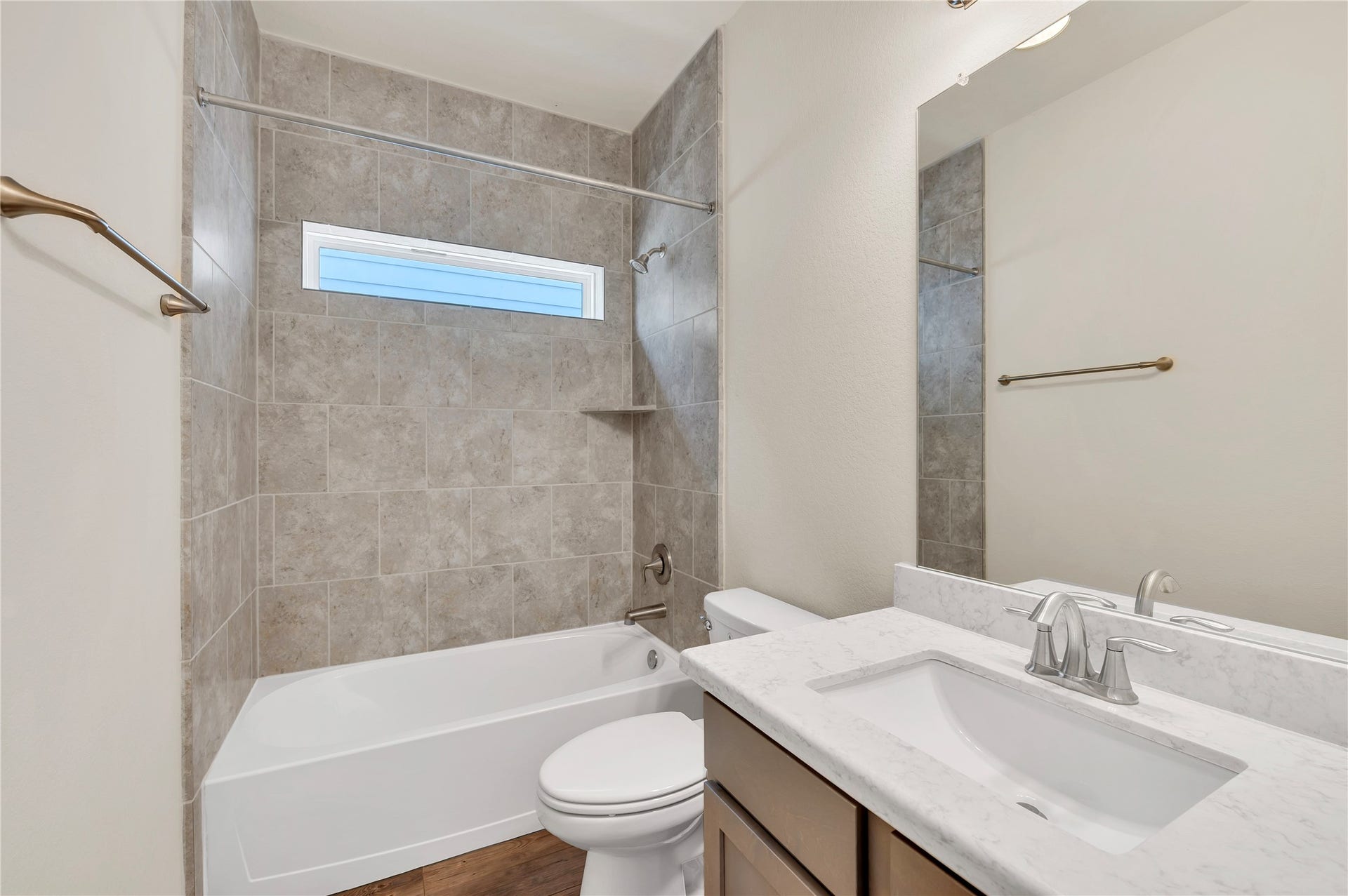 1849 Kenley Way, Alvin, TX 77511 Modern bathroom featuring a sleek vanity with a quartz countertop, a bathtub with elegant tile surround, and a large mirror enhancing the space.