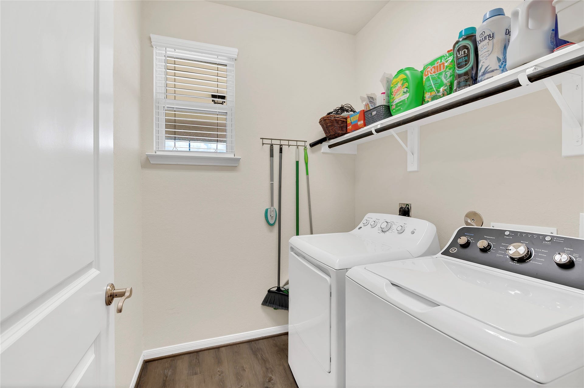 1849 Kenley Way, Alvin, TX 77511 Bright and functional laundry room with ample shelving for storage, and a convenient hanging rack for cleaning essentials.